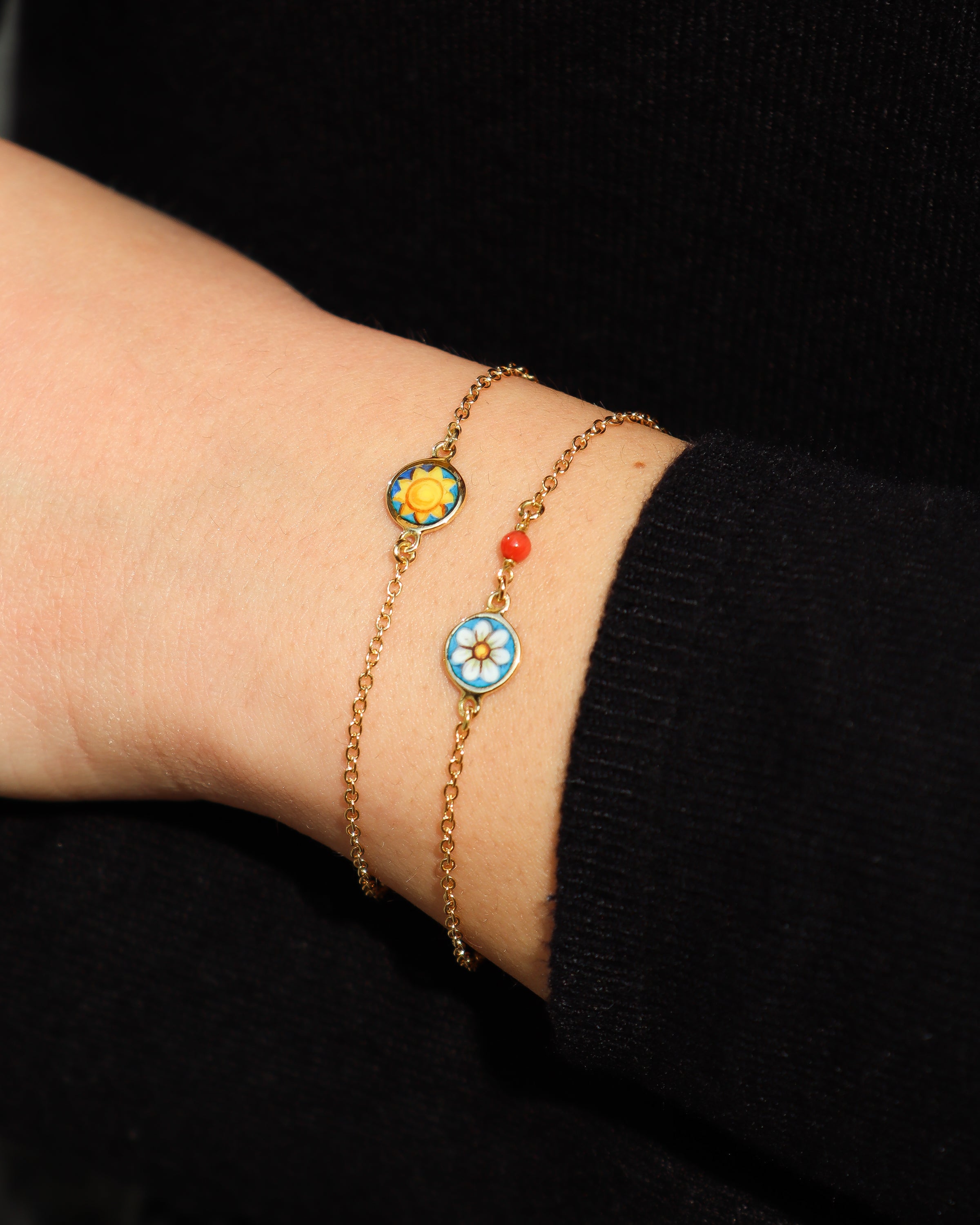 Bracciale in oro giallo 18 carati con margherita dipinta a mano in smalto a fuoco e perlina in corallo rosso.