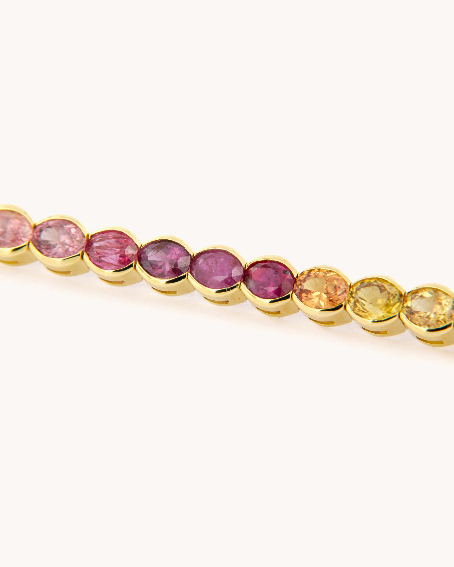 Bracciale tennis in oro giallo 18 carati, impreziosito da zaffiri naturali multicolore dal taglio ovale.