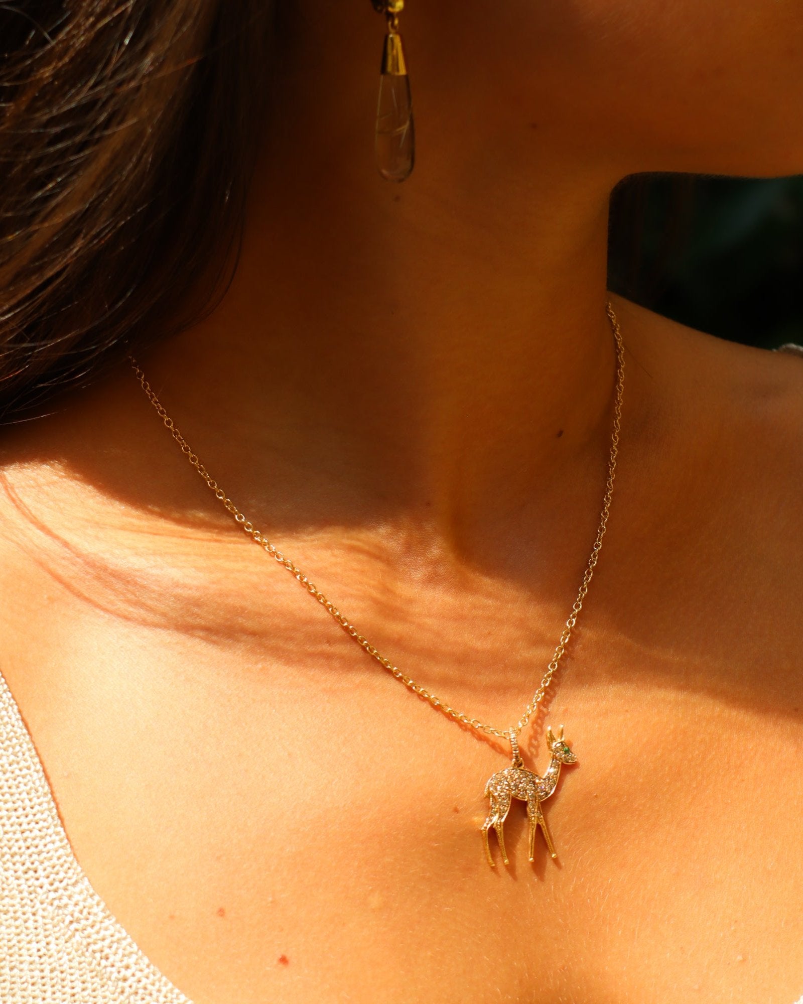 Dettaglio di ciondolo cerbiatto in oro rosa 18K con pavé di diamanti brown e smeraldo