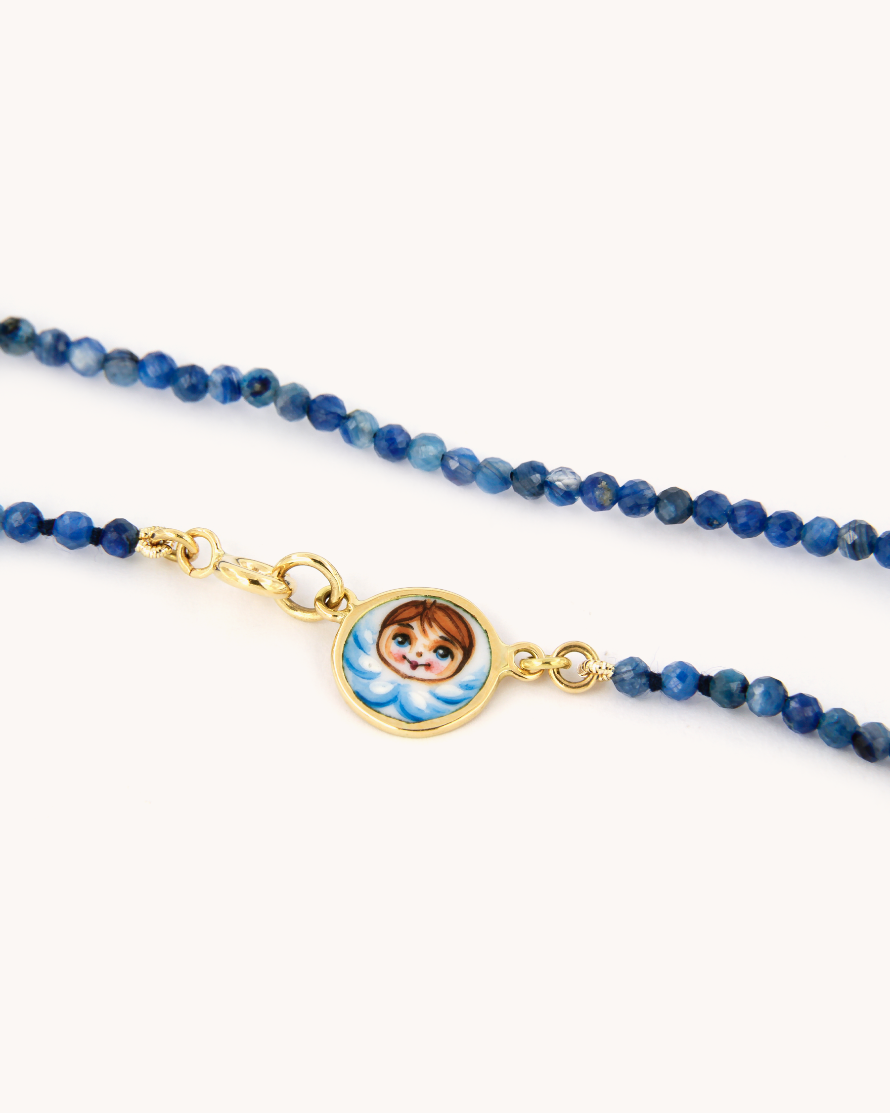 Collana Coloris con perline di cianite, chiusura in oro giallo 18 carati e pendente angelo smaltato a mano.