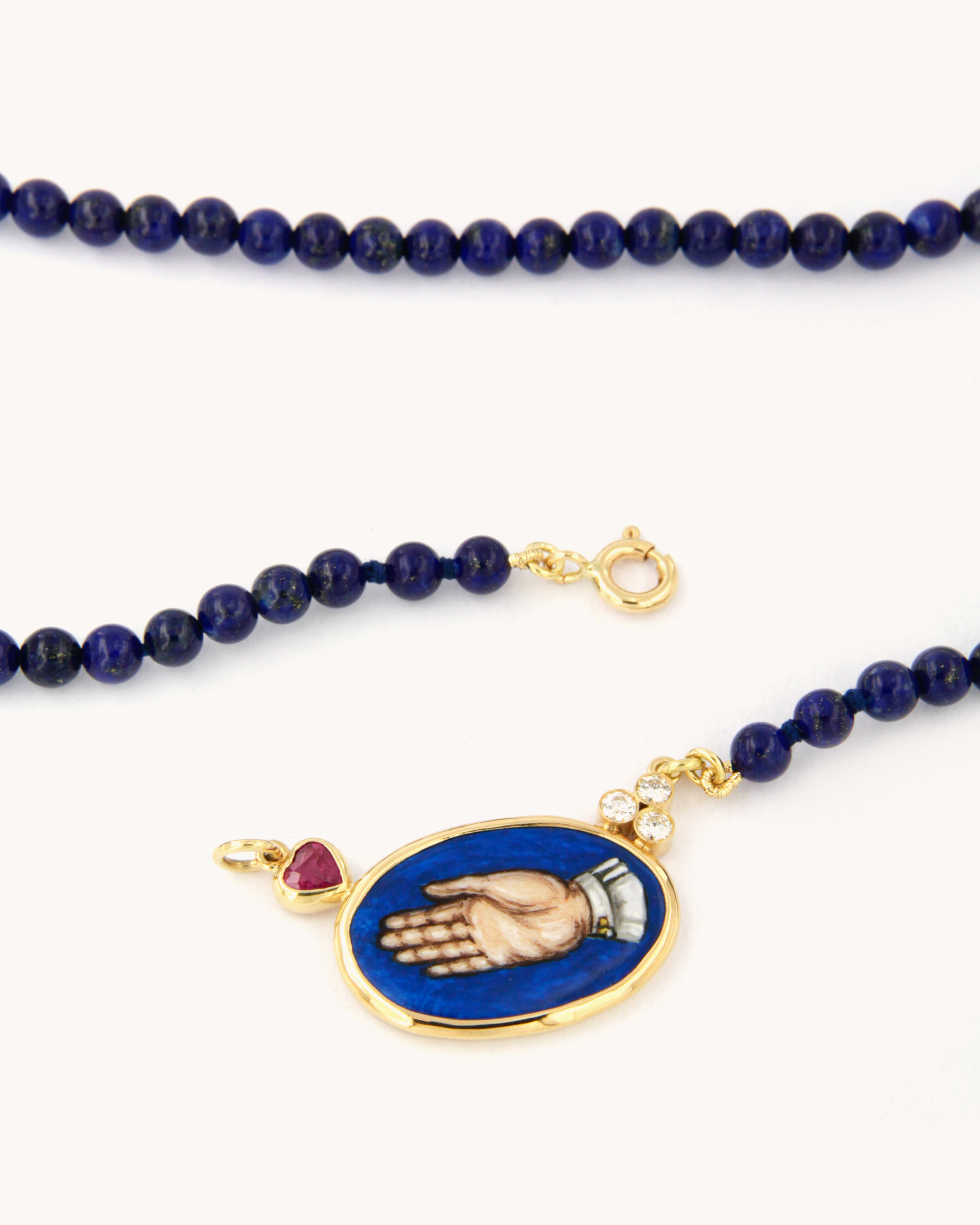 Collana Coloris in lapislazzuli con piastra in smalto a fuoco raffigurante la mano "Sono Qui per Te", rubino a cuore, diamanti e oro giallo 18K.