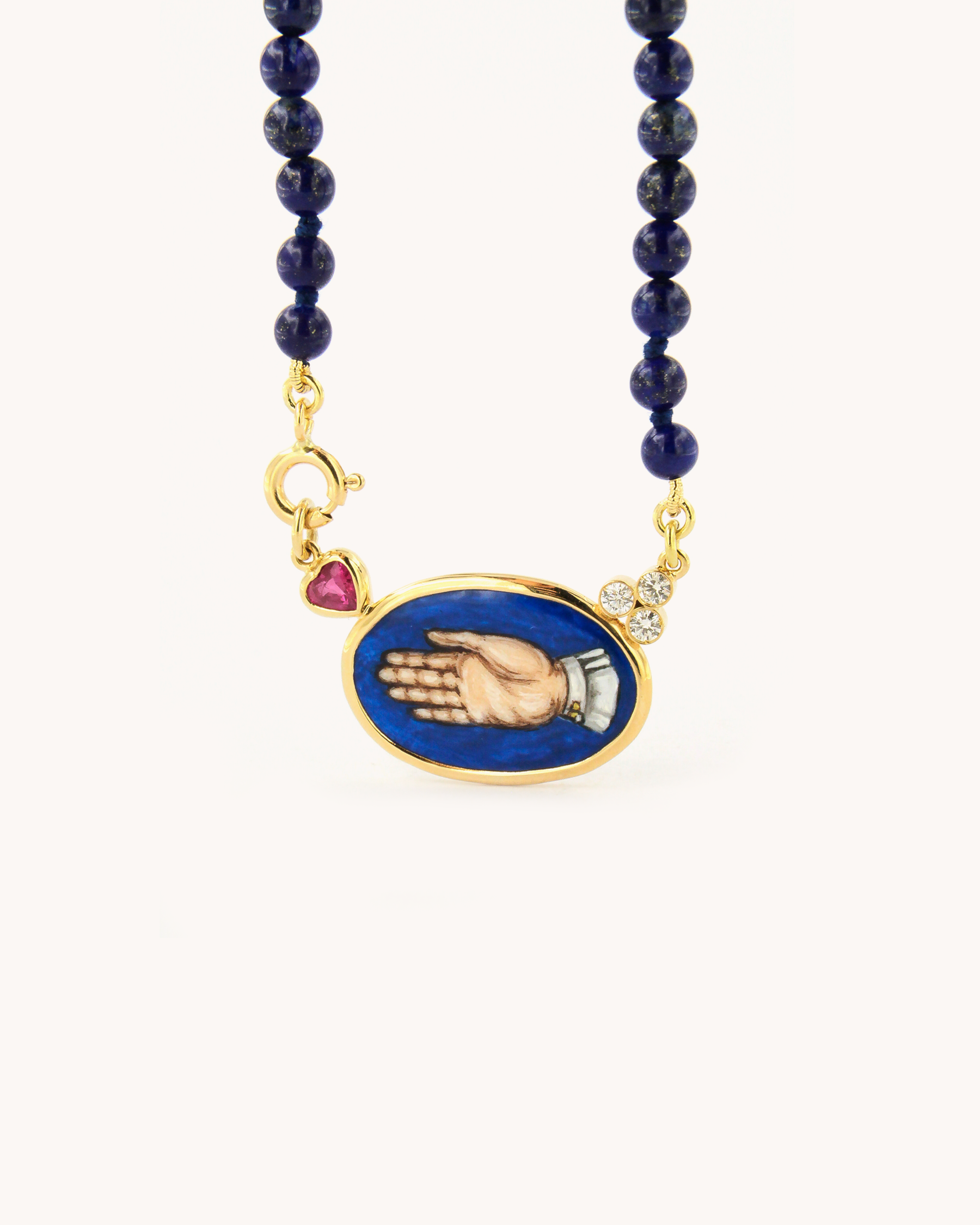 Collana Coloris in lapislazzuli con piastra in smalto a fuoco raffigurante la mano "Sono Qui per Te", rubino a cuore, diamanti e oro giallo 18K.