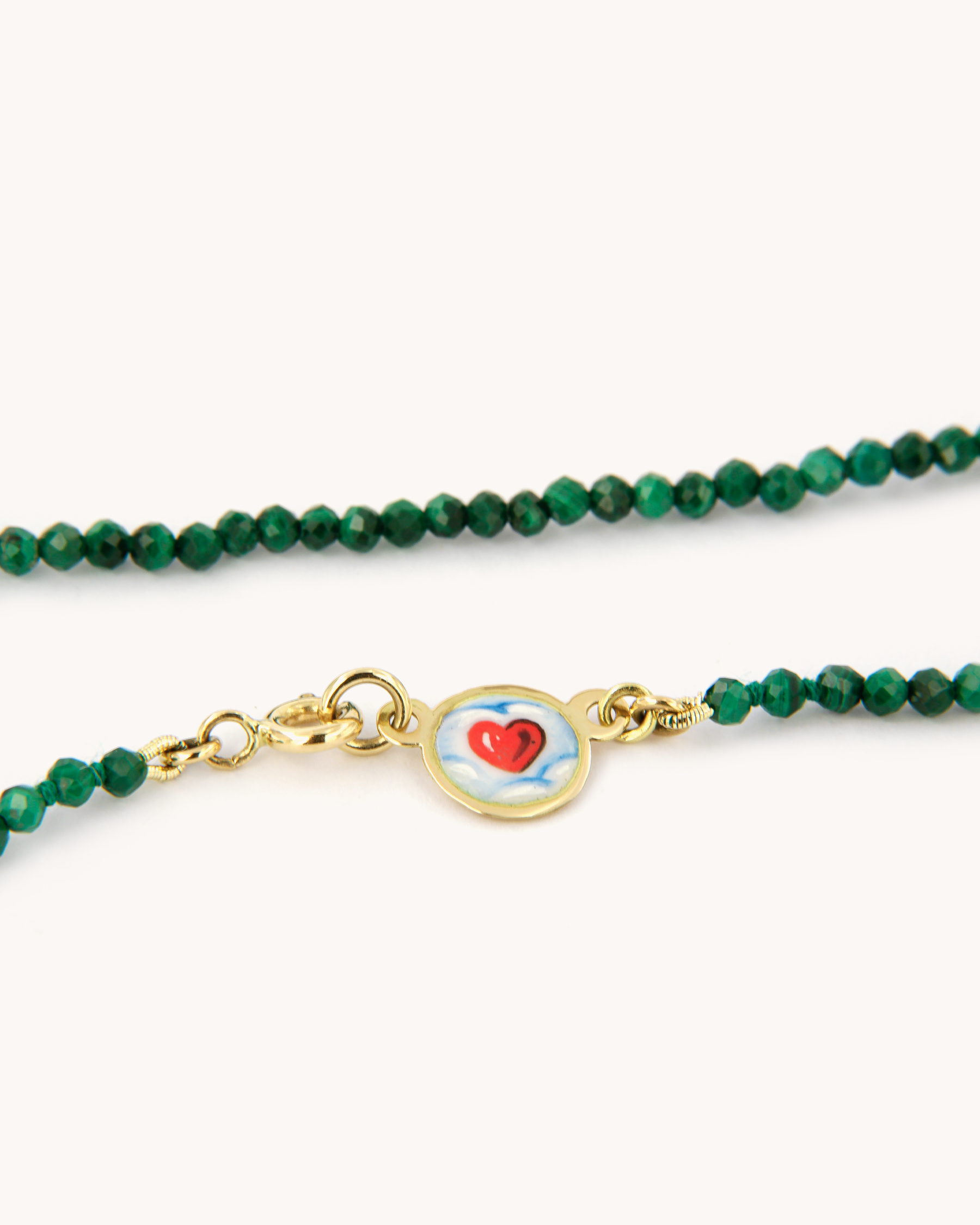Dettaglio della Collana Coloris con perline di malachite, chiusura in oro giallo 18 carati e cuore tra le nuvole dipinto a mano in smalto a fuoco.