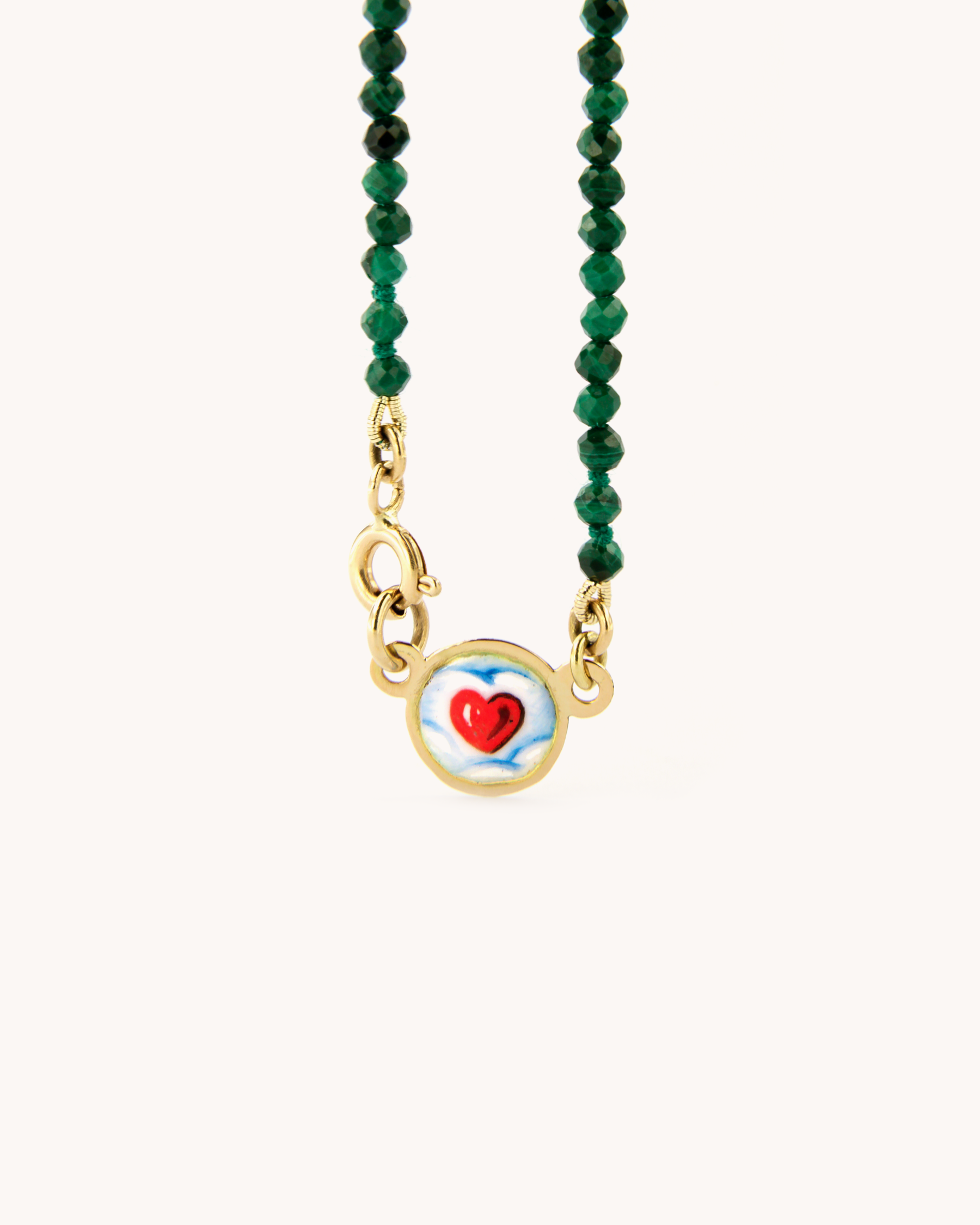 Dettaglio della Collana Coloris con perline di malachite, chiusura in oro giallo 18 carati e cuore tra le nuvole dipinto a mano in smalto a fuoco.