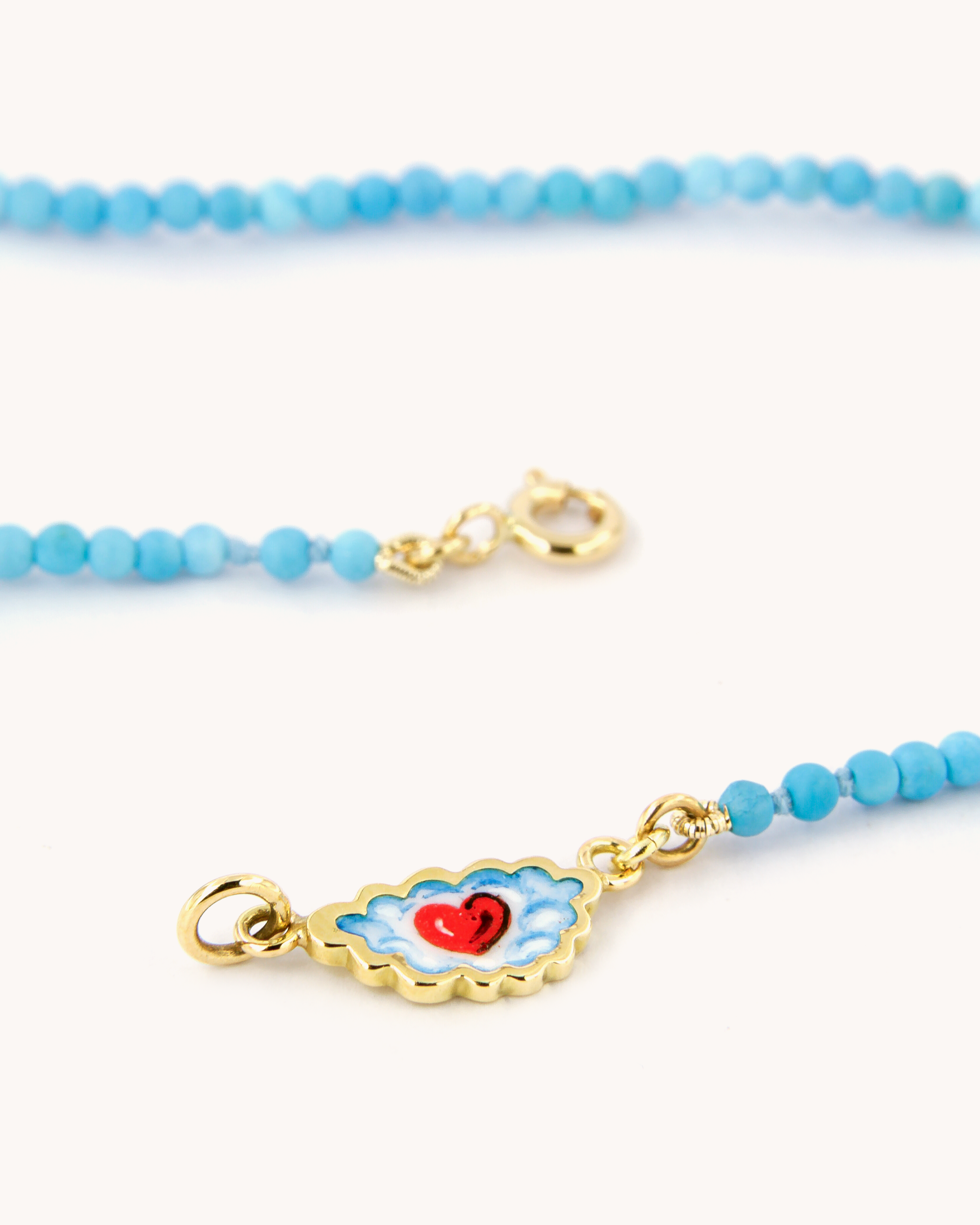 Dettaglio della Collana Coloris con perline di pasta di turchese, chiusura in oro giallo 18 carati e cuore tra le nuvole dipinto a mano in smalto a fuoco.
