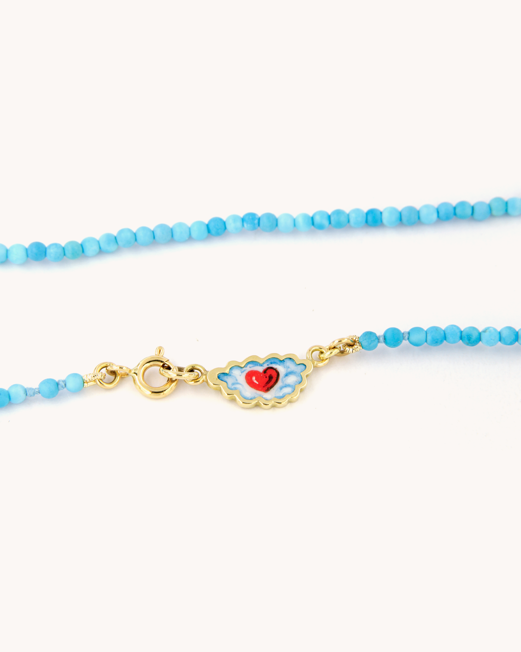 Dettaglio della Collana Coloris con perline di pasta di turchese, chiusura in oro giallo 18 carati e cuore tra le nuvole dipinto a mano in smalto a fuoco.