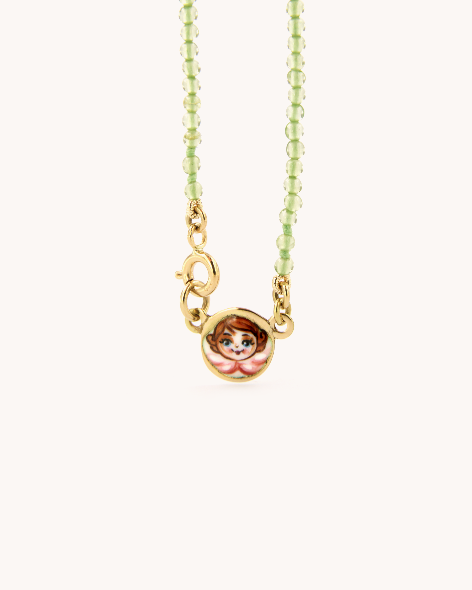 Collana Coloris con perline di peridoto e angelo rosa in smalto a fuoco indossata.