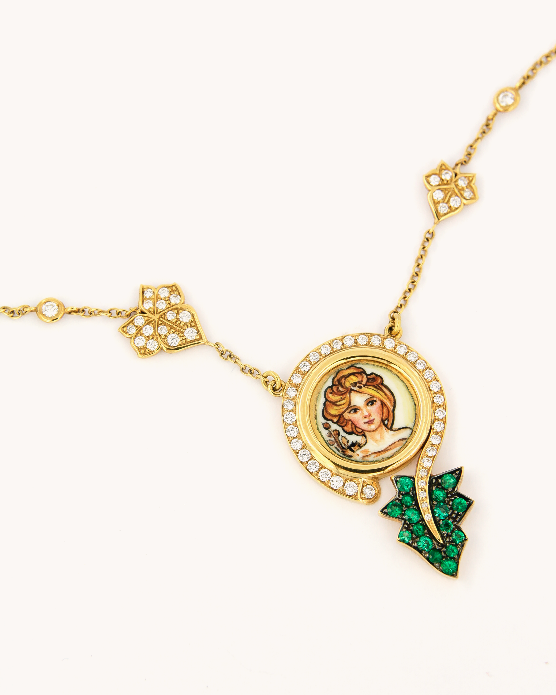 Collana in oro giallo 18 carati con pendente Madre Natura in smalto figurativo dipinto a mano, impreziosito da diamanti e smeraldi.