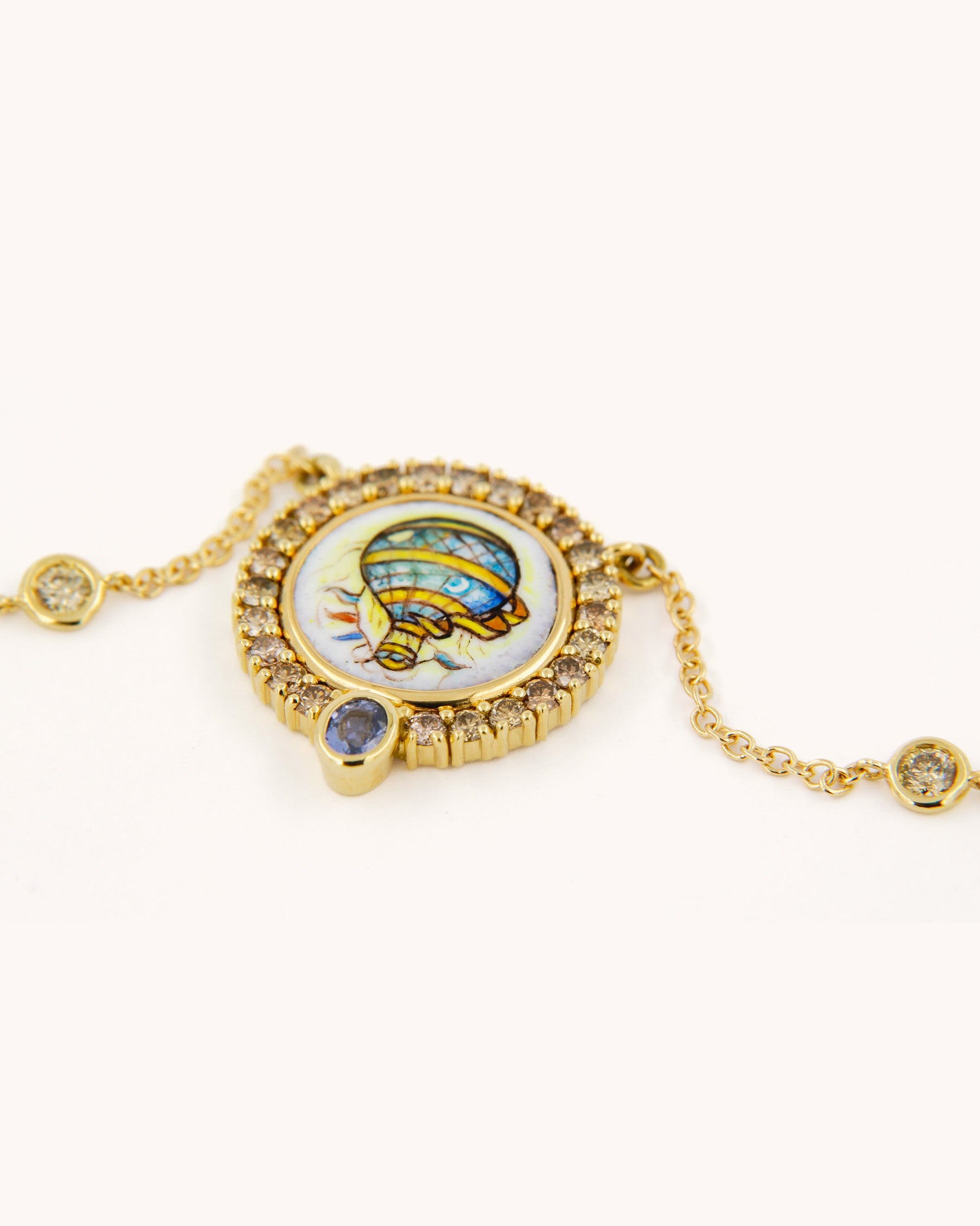 Collana in oro giallo 18K con ciondolo a forma di mongolfiera dipinto a mano in smalto a fuoco, incorniciato da diamanti brown e arricchito da zaffiro.