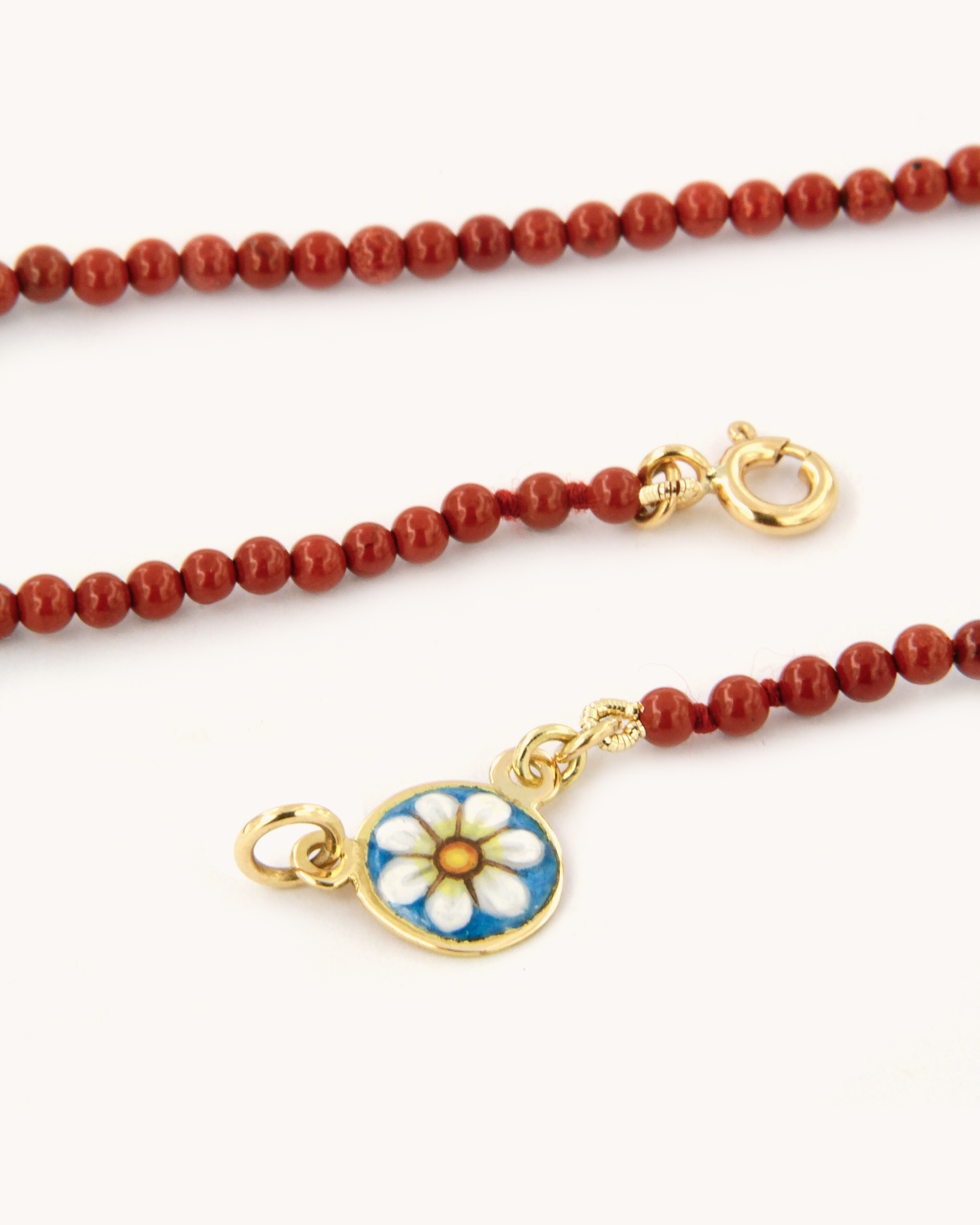 Collana con perle di diaspro rosso e piastrina in oro giallo 18K decorata con margherita in smalto a fuoco dipinto a mano.