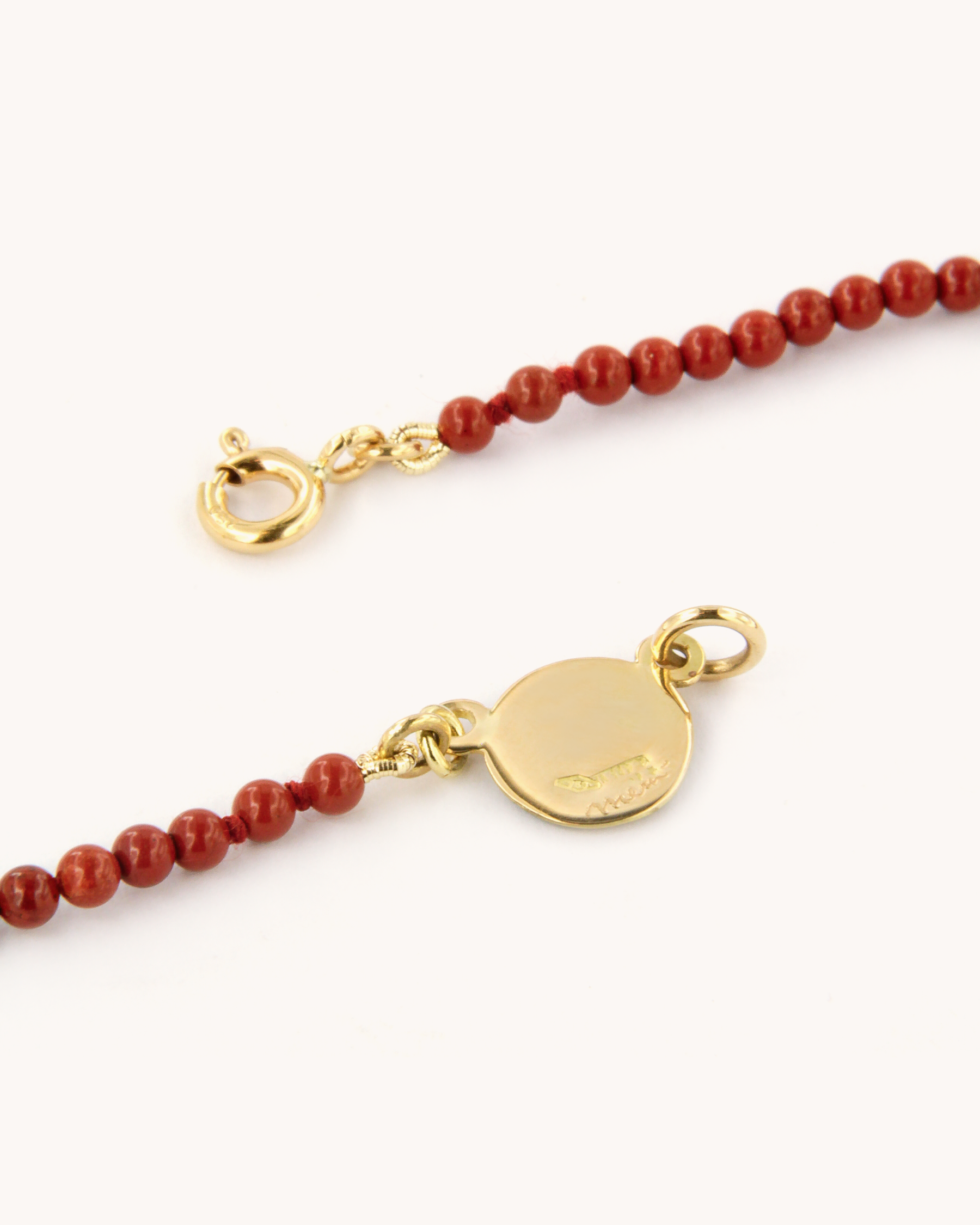 Collana con perle di diaspro rosso e piastrina in oro giallo 18K decorata con margherita in smalto a fuoco dipinto a mano.