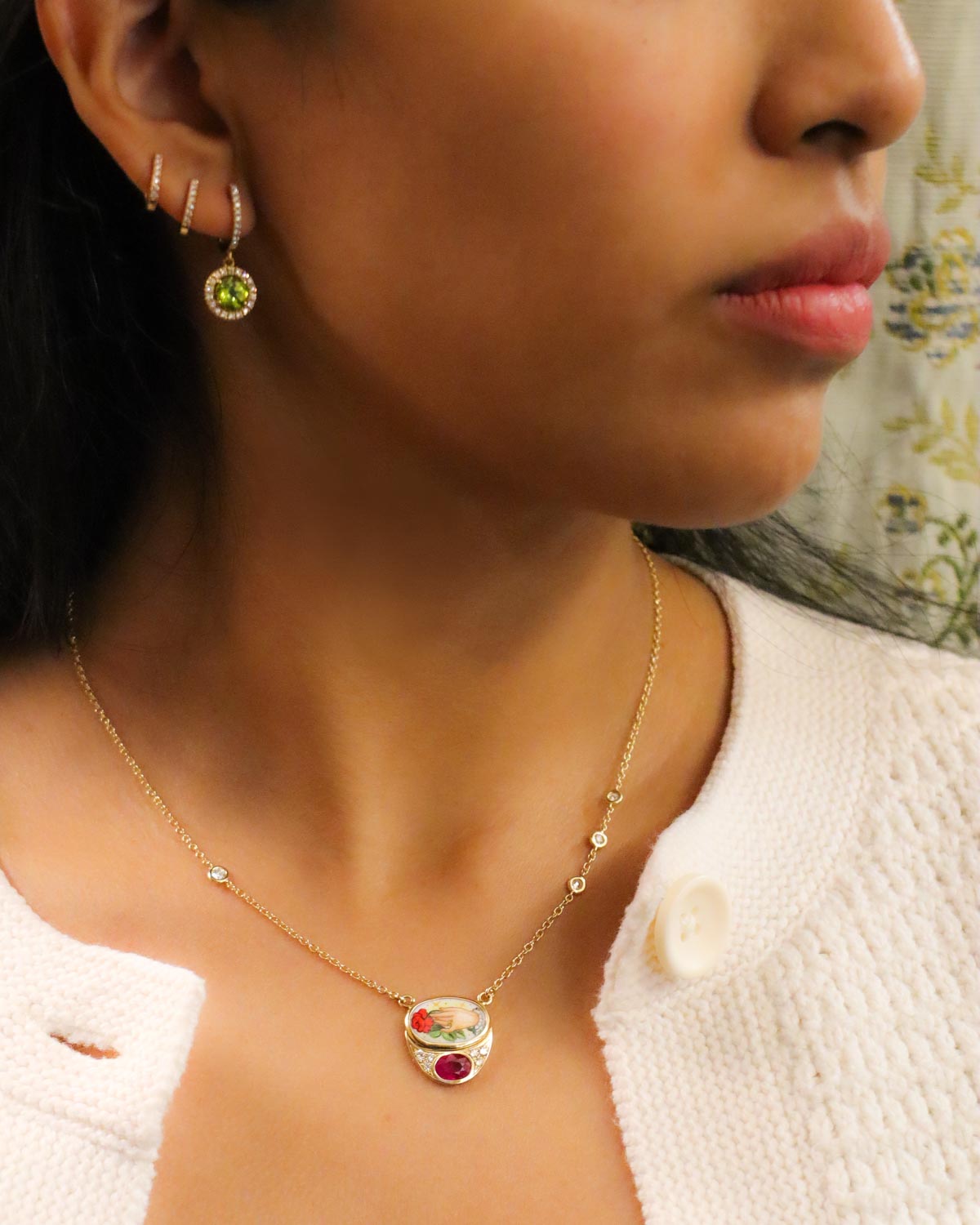 Collana in oro giallo 18 carati con pendente in smalto a fuoco raffigurante la scena “Ti Do una Rosa”, impreziosita da un rubino centrale e diamanti bianchi.