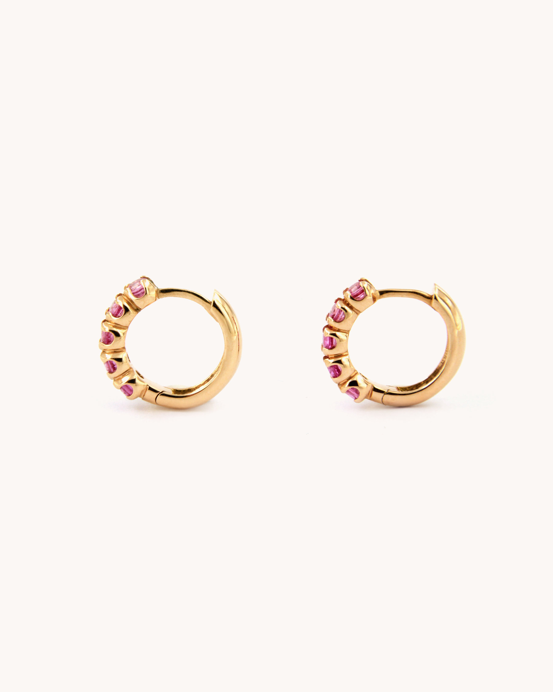 Orecchini a cerchio in oro rosa 18 carati con zaffiri rosa incastonati lungo il profilo.