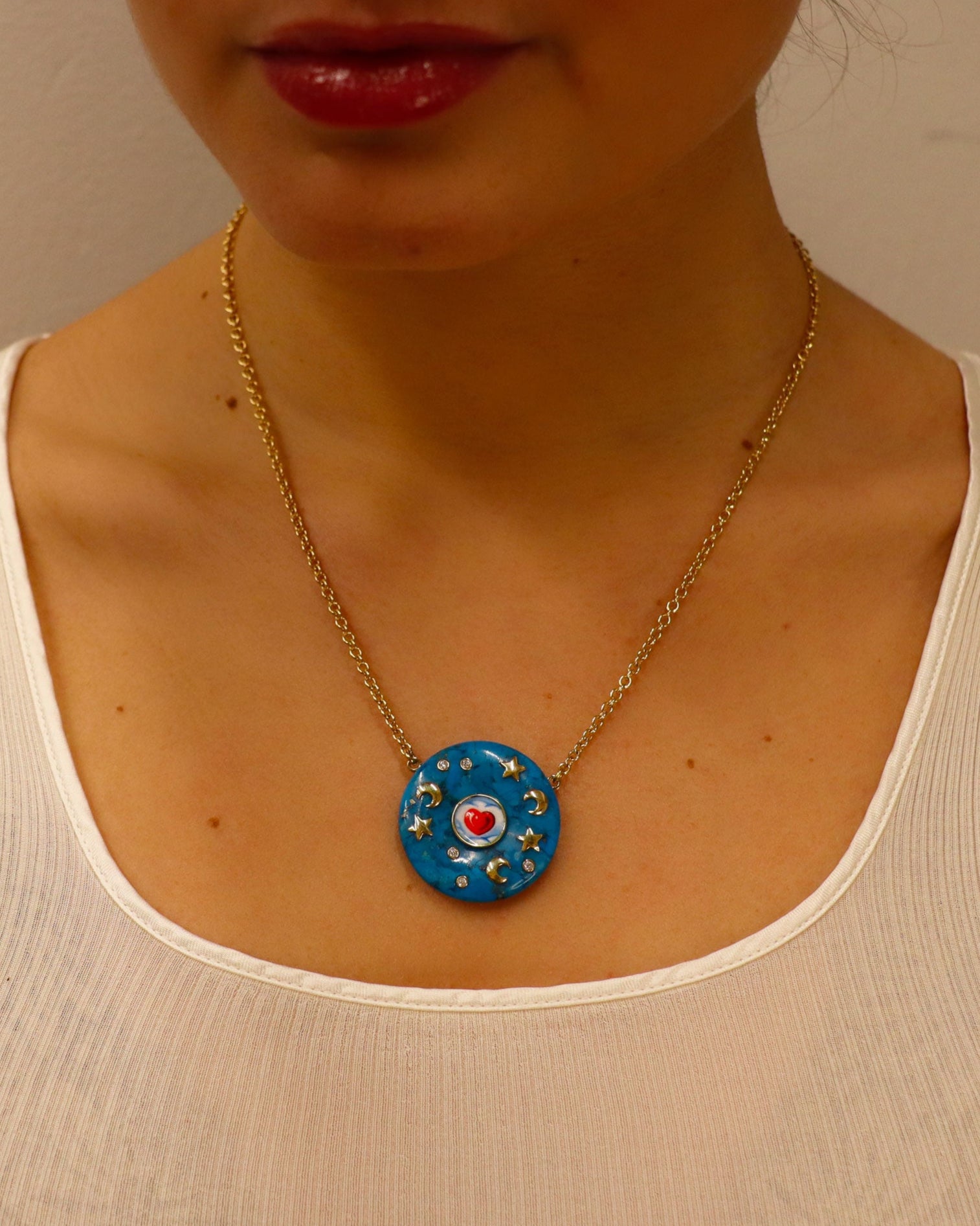 Collana in oro giallo 18 carati con rondella in turchese decorata da lune e stelle dorate in smalto dipinto a mano e diamanti bianchi.