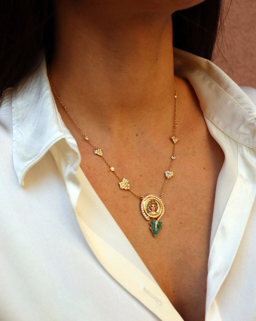 Collana in oro giallo 18 carati con pendente Madre Natura in smalto figurativo dipinto a mano, impreziosito da diamanti e smeraldi.