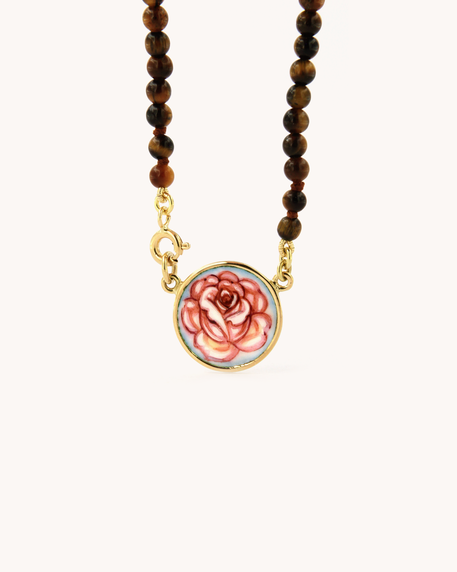 Dettaglio della collana Coloris con perline di occhio di tigre e piastra con rosa dipinta a mano in smalto a fuoco, incorniciata in oro giallo 18 carati.