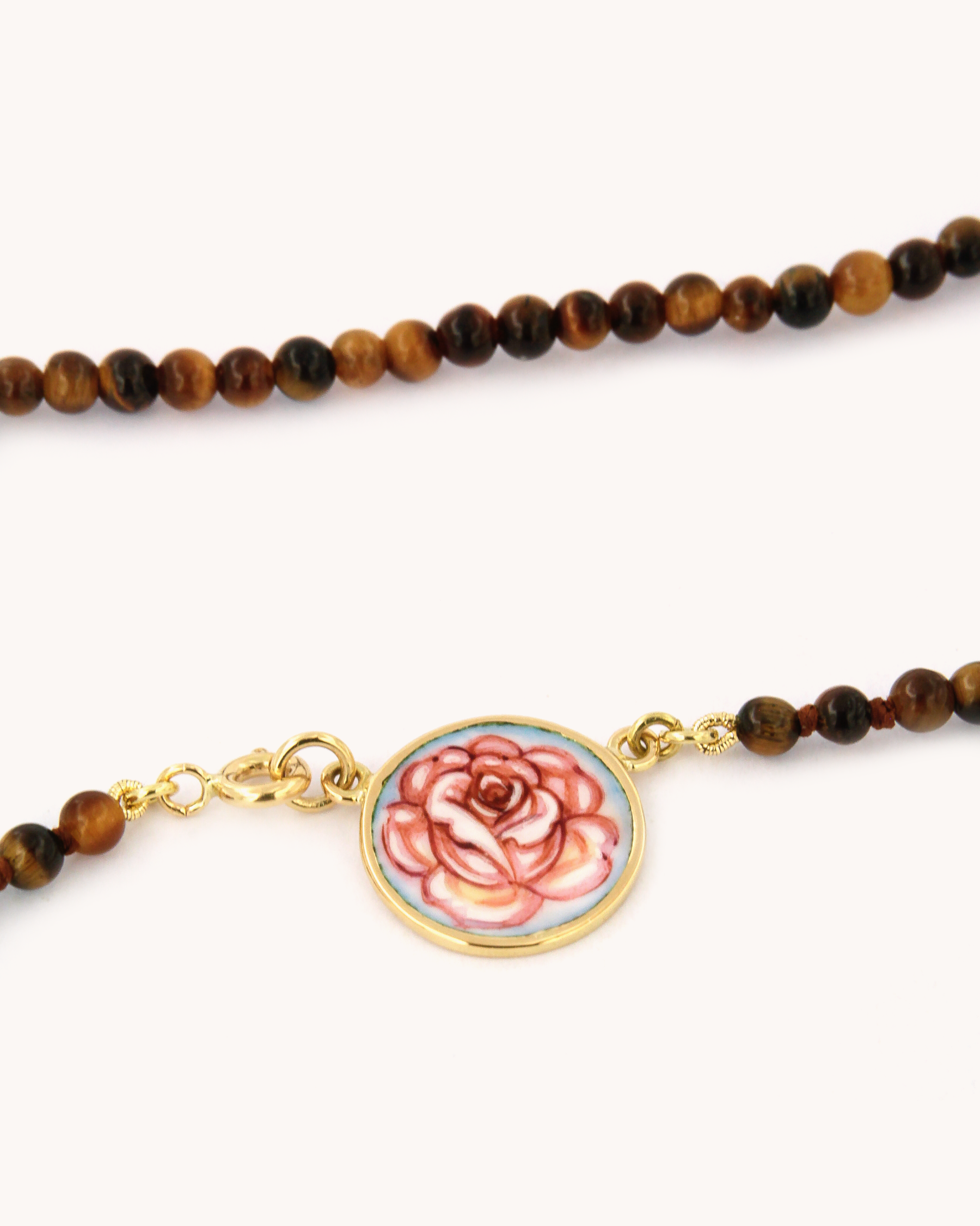 Dettaglio della collana Coloris con perline di occhio di tigre e piastra con rosa dipinta a mano in smalto a fuoco, incorniciata in oro giallo 18 carati.