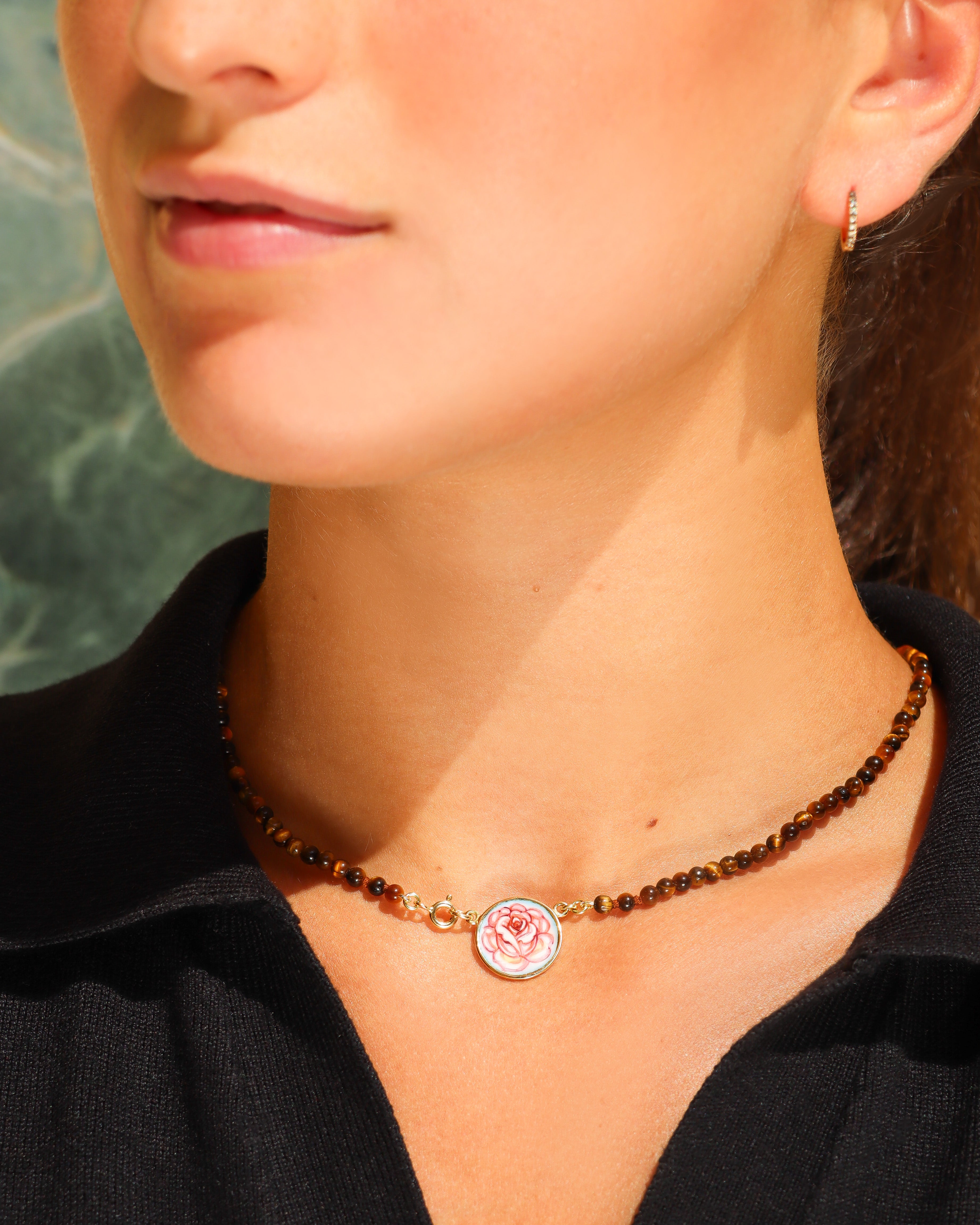 Dettaglio della collana Coloris con perline di occhio di tigre e piastra con rosa dipinta a mano in smalto a fuoco, incorniciata in oro giallo 18 carati.