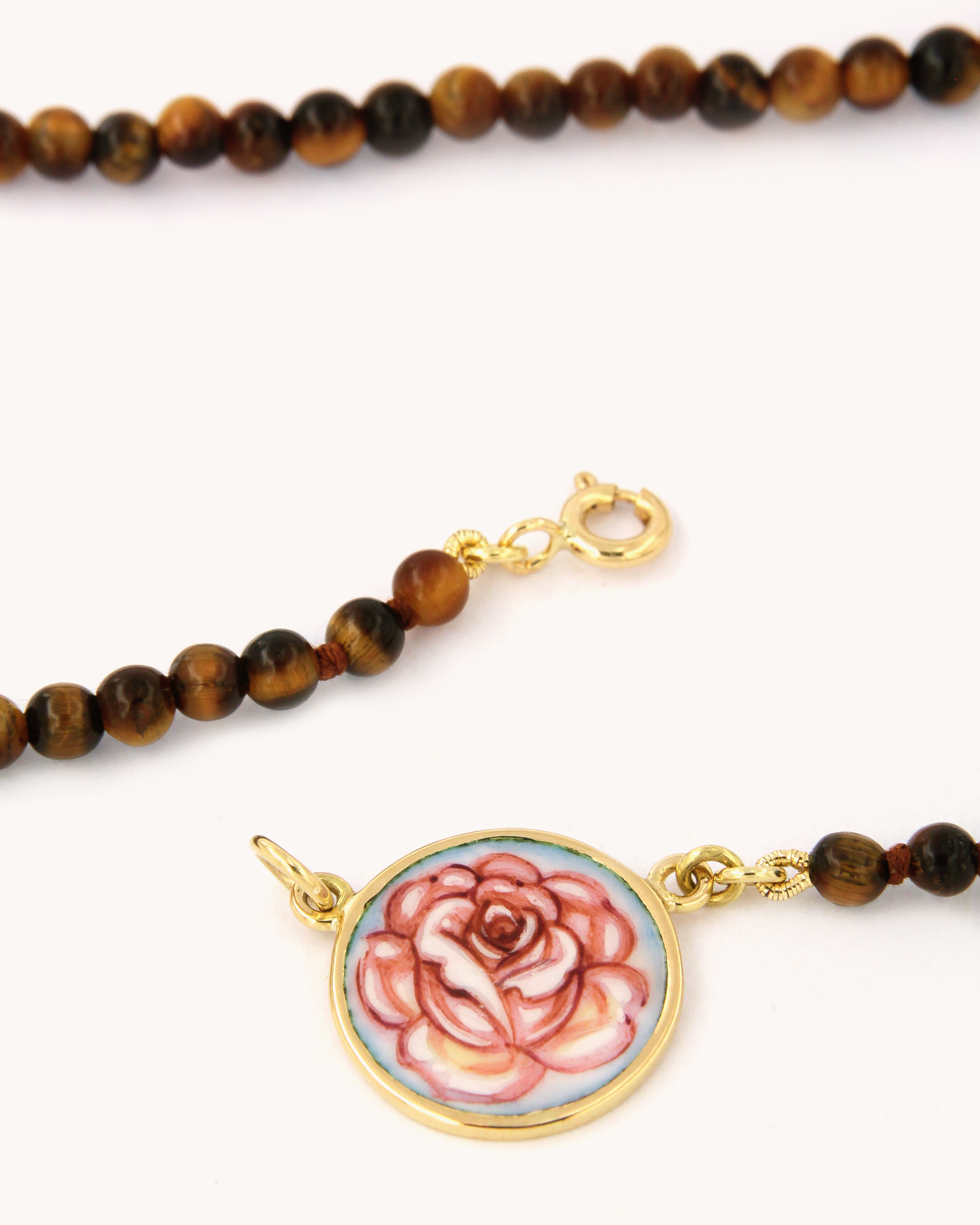 Dettaglio della collana Coloris con perline di occhio di tigre e piastra con rosa dipinta a mano in smalto a fuoco, incorniciata in oro giallo 18 carati.