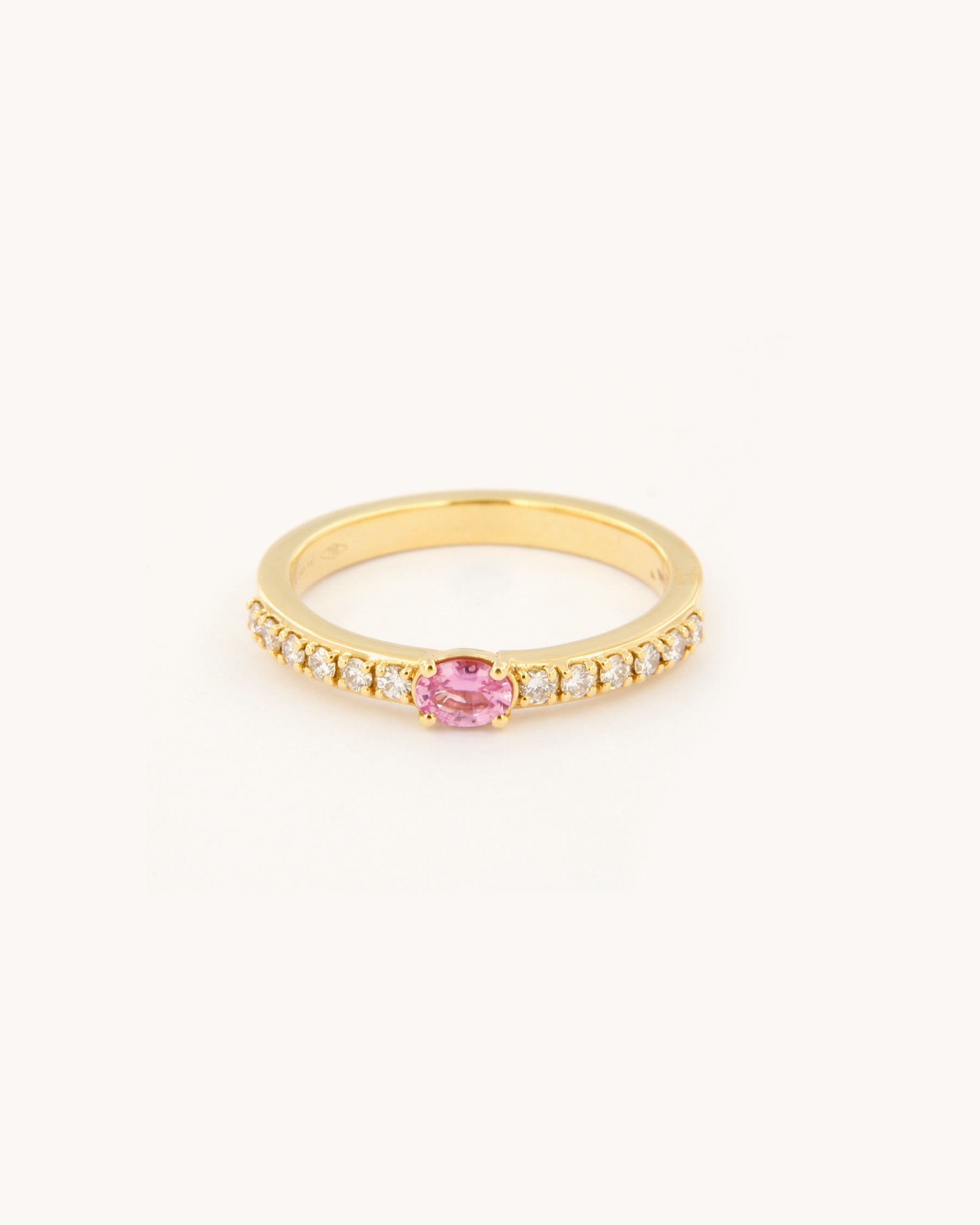 Anello oro 18K con zaffiro rosa ovale centrale e diamanti laterali.
