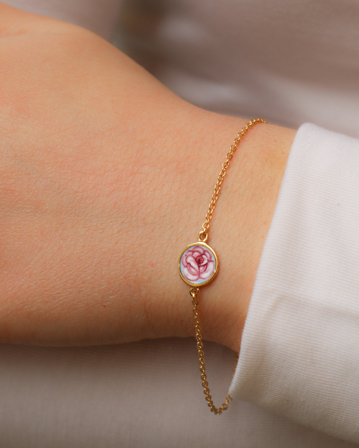 Bracciale Rosa in oro giallo 18K con rosa dipinta a mano in smalto a fuoco, indossato al polso