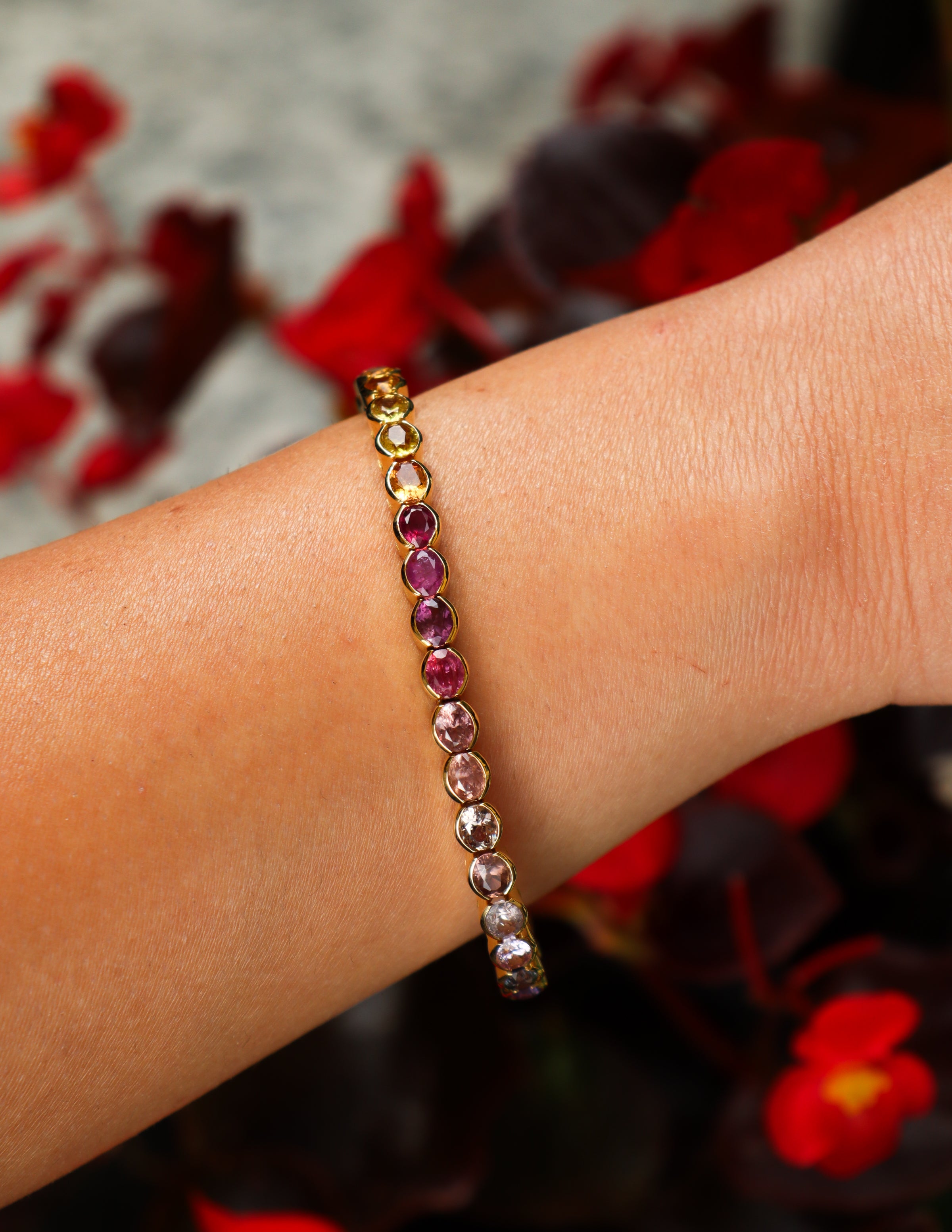 Bracciale tennis in oro giallo 18 carati, impreziosito da zaffiri naturali multicolore dal taglio ovale.