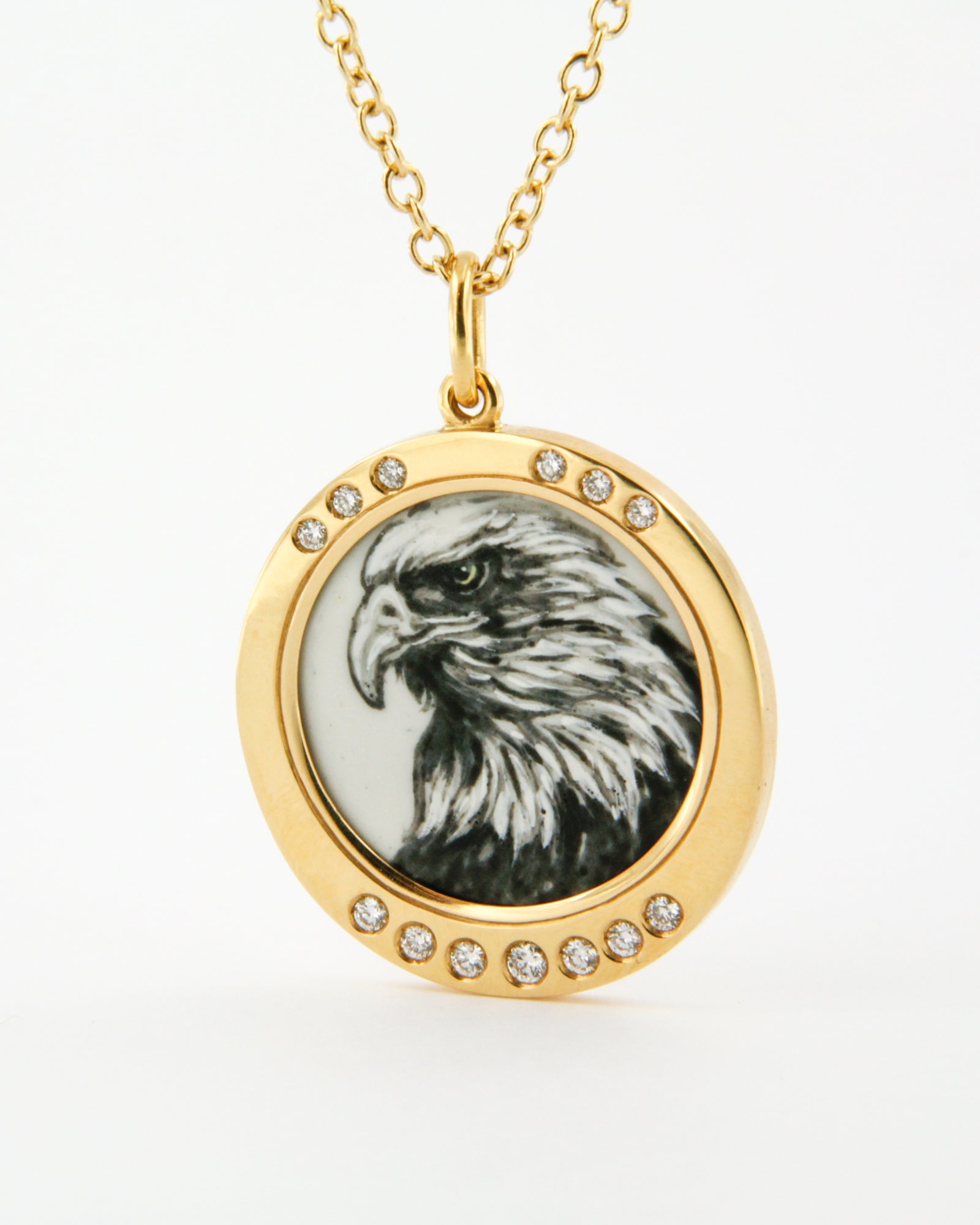 Ciondolo in oro giallo 18K con aquila in smalto a fuoco dipinta a mano e cornice di diamanti bianchi su sfondo blu.
