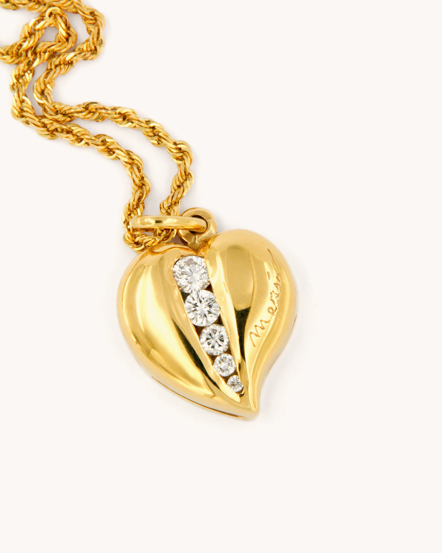 Ciondolo in oro giallo 18 carati a forma di cuore con diamanti bianchi di diverse dimensioni.