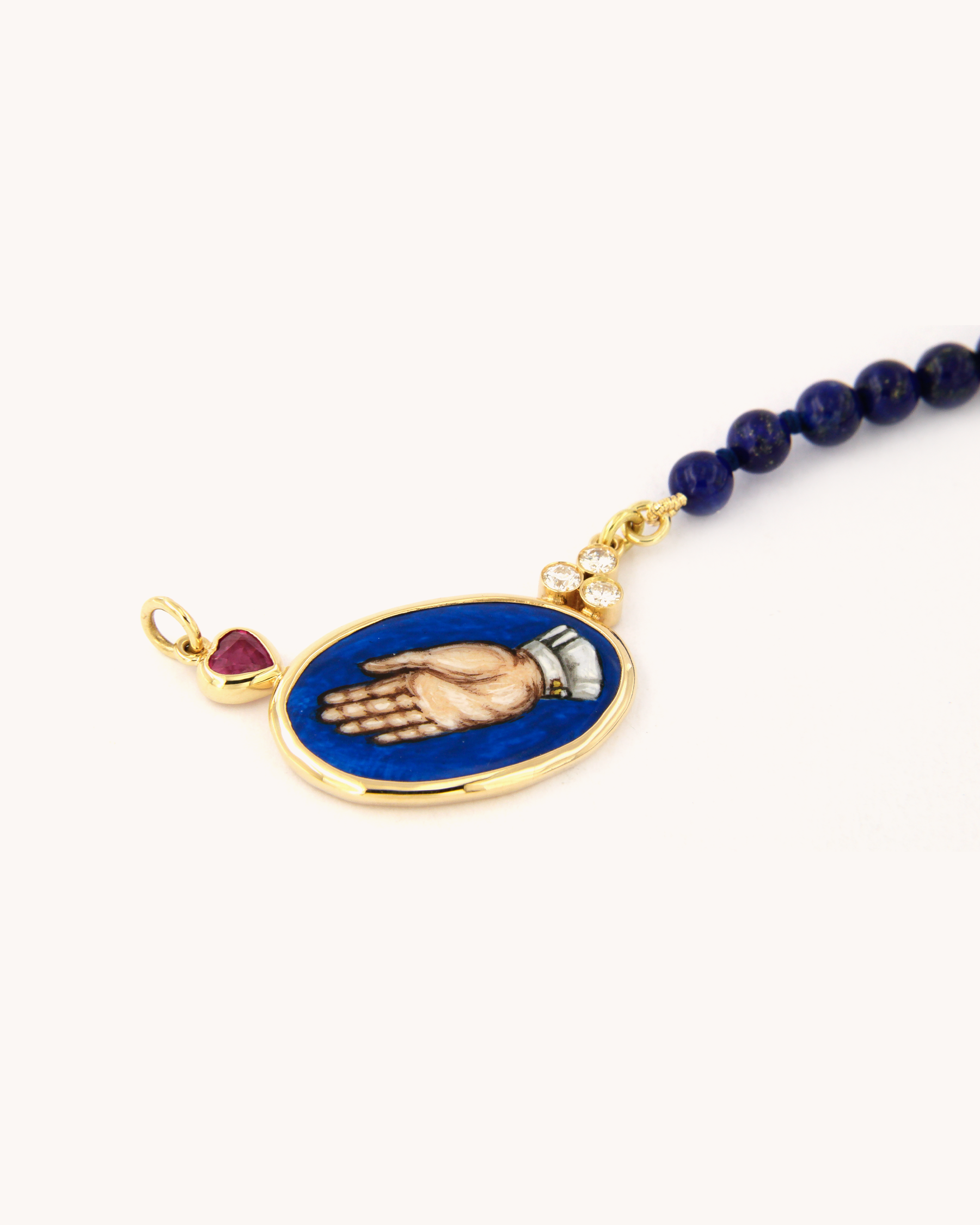 Collana Coloris in lapislazzuli con piastra in smalto a fuoco raffigurante la mano "Sono Qui per Te", rubino a cuore, diamanti e oro giallo 18K.