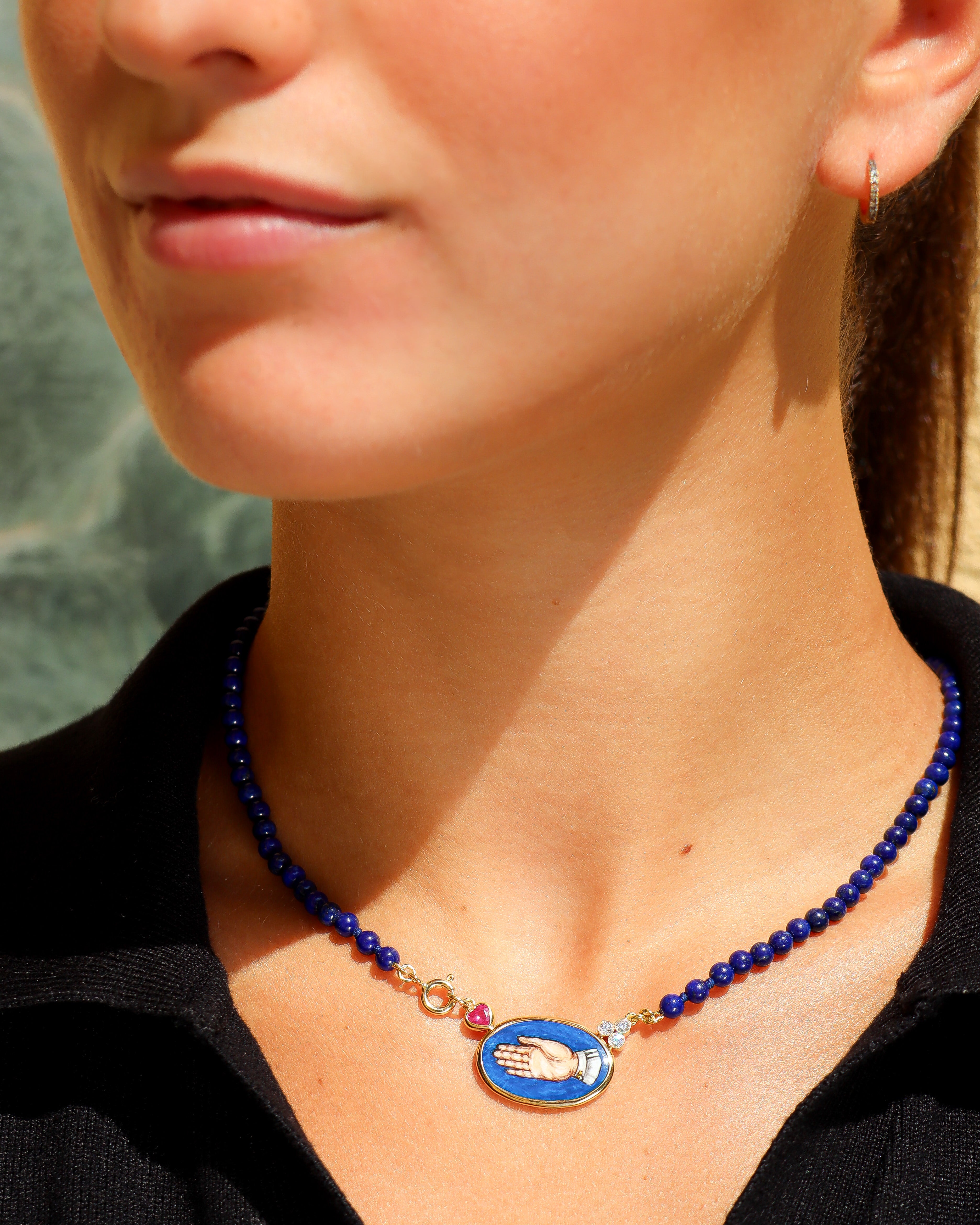 Collana Coloris in lapislazzuli con piastra in smalto a fuoco raffigurante la mano "Sono Qui per Te", rubino a cuore, diamanti e oro giallo 18K.
