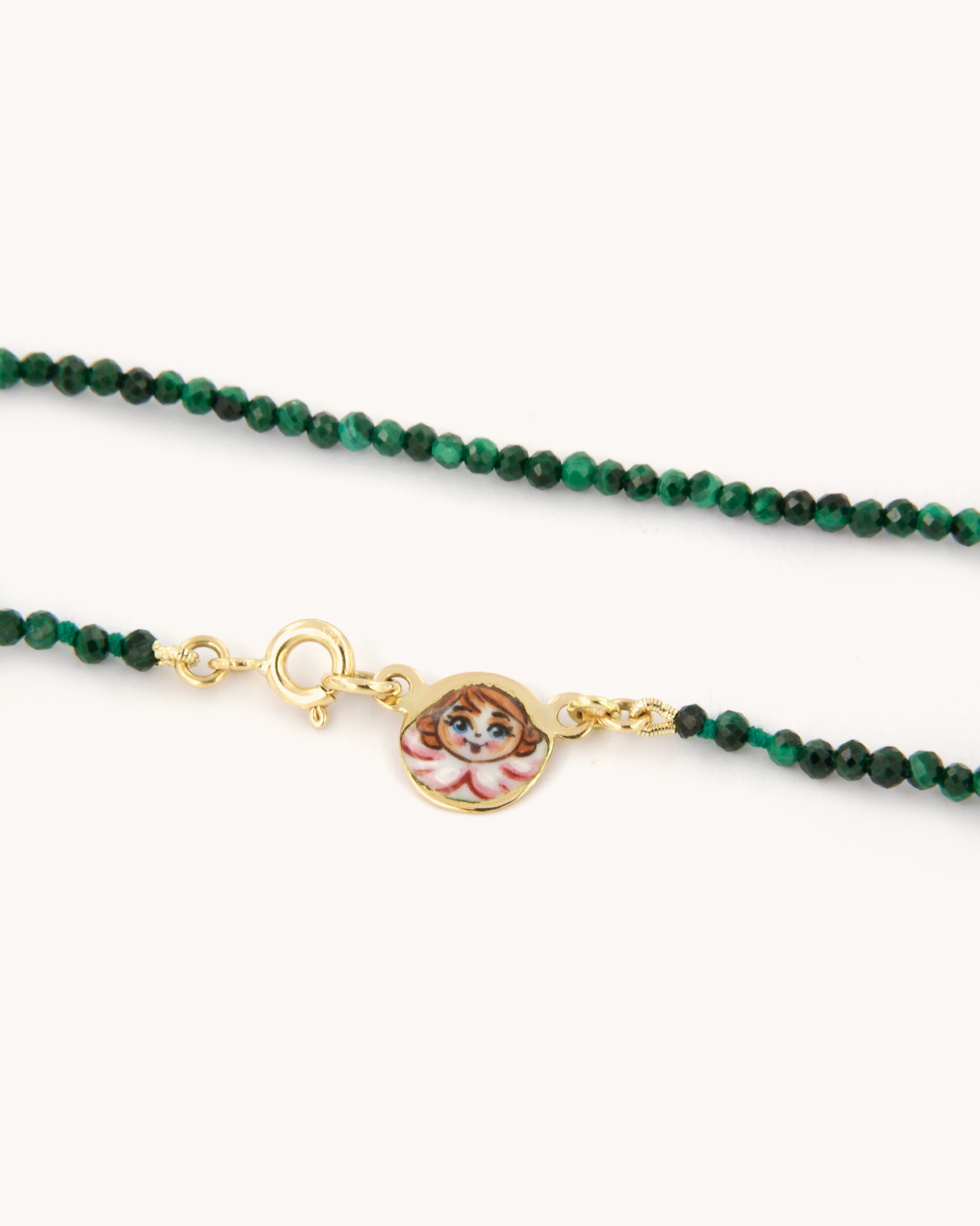 Collana in malachite con piastrina in oro giallo 18 carati decorata con angelo in smalto a fuoco dipinto a mano. Un gioiello firmato Merù Gioielli.