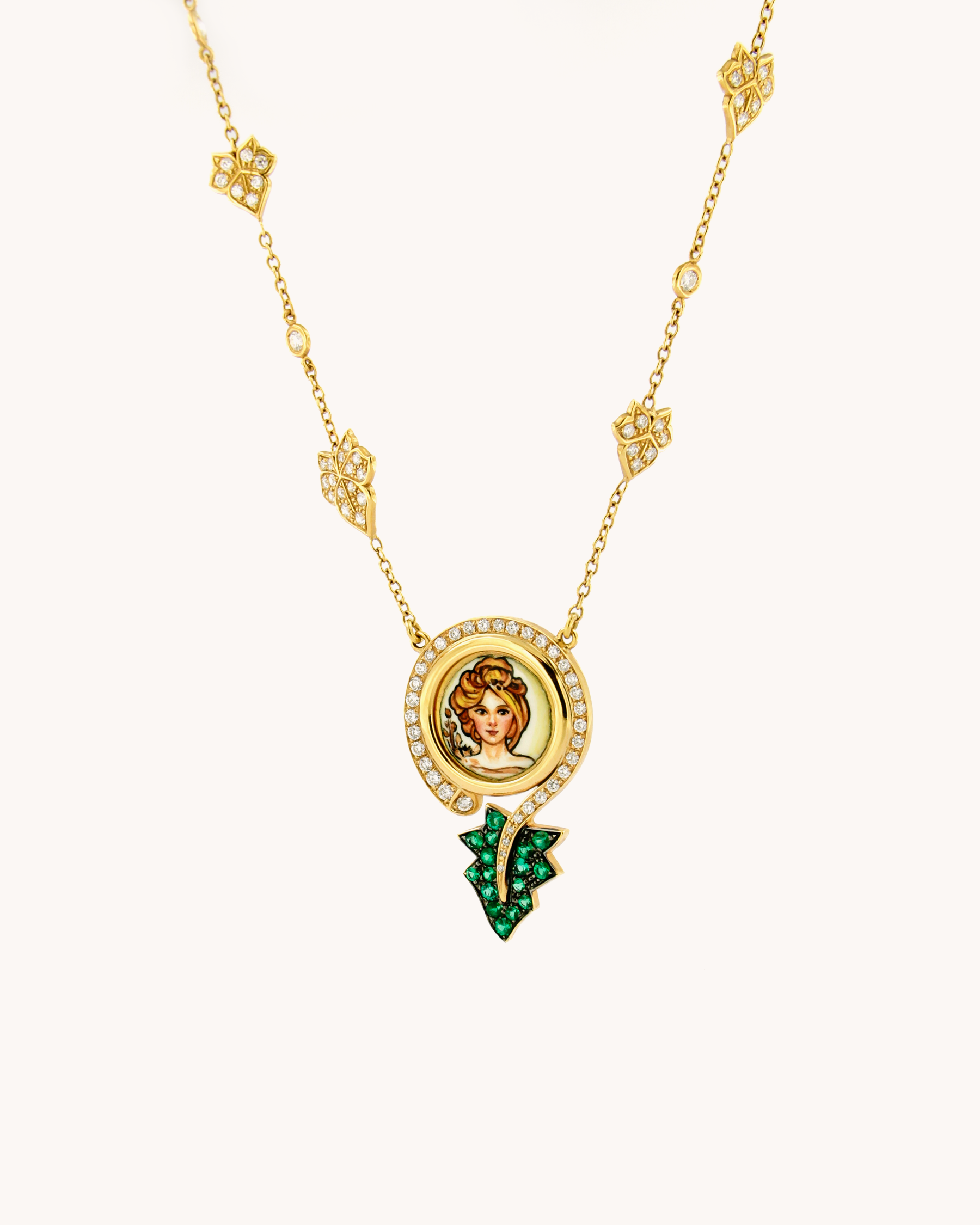 Collana in oro giallo 18 carati con pendente Madre Natura in smalto figurativo dipinto a mano, impreziosito da diamanti e smeraldi.
