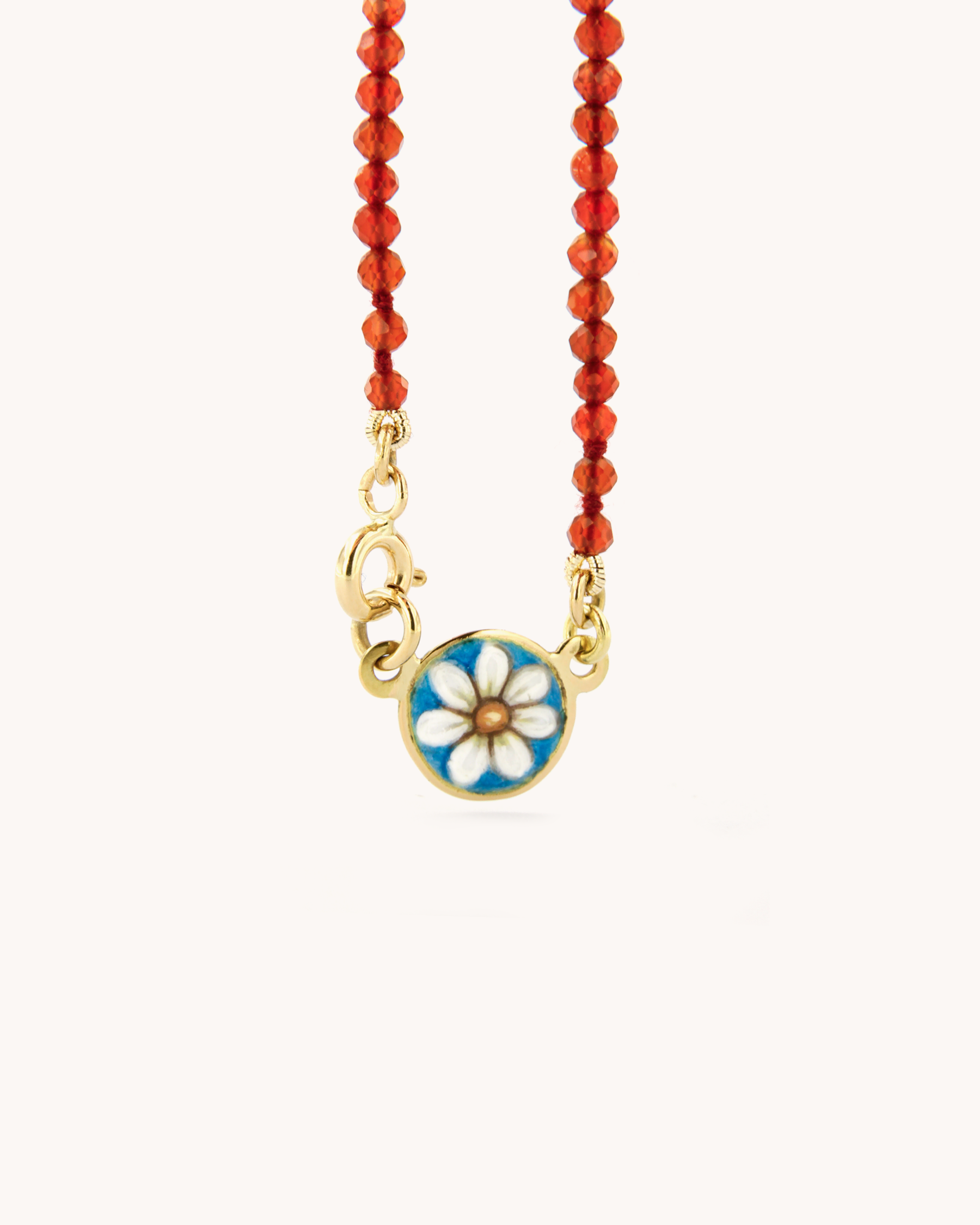 Collana infilata a filo semplice con perline di corniola e chiusura in oro giallo 18 carati, impreziosita da una piastrina decorata con angelo in smalto a fuoco dipinto a mano.