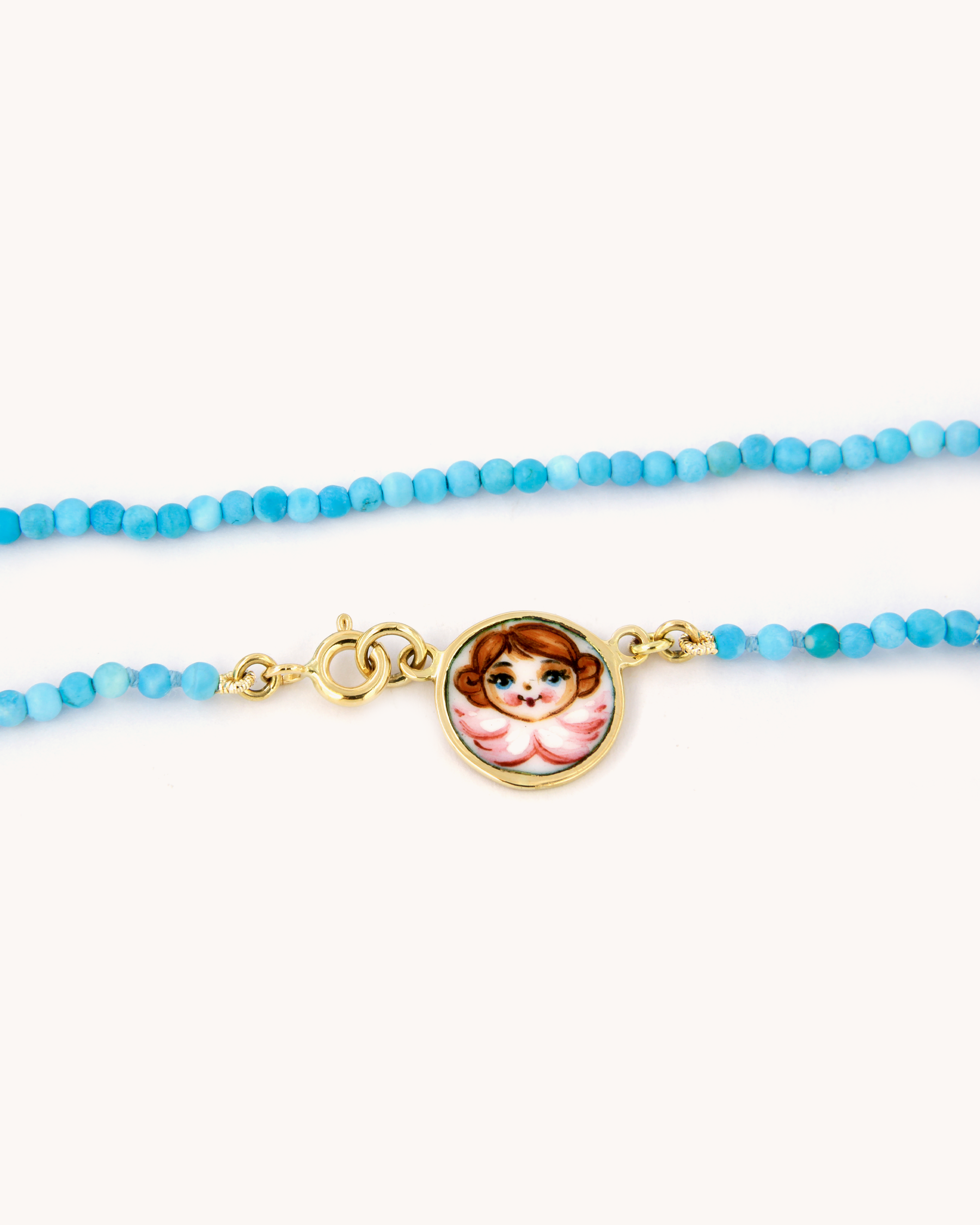 Collana Coloris con perline di pasta di turchese, pendente angelo smaltato a fuoco e chiusura in oro giallo 18 carati