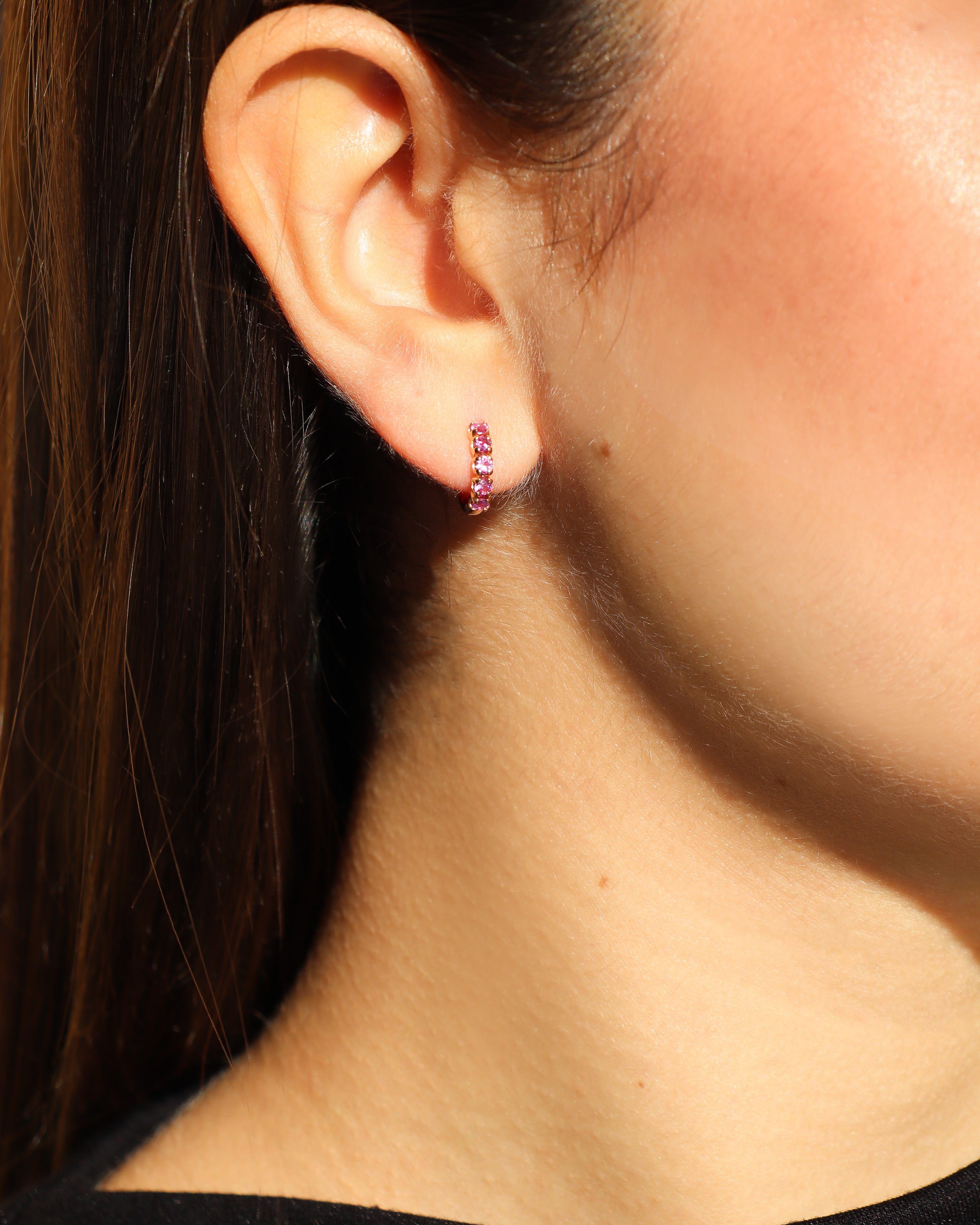 Orecchini a cerchio in oro rosa 18 carati con zaffiri rosa incastonati lungo il profilo.
