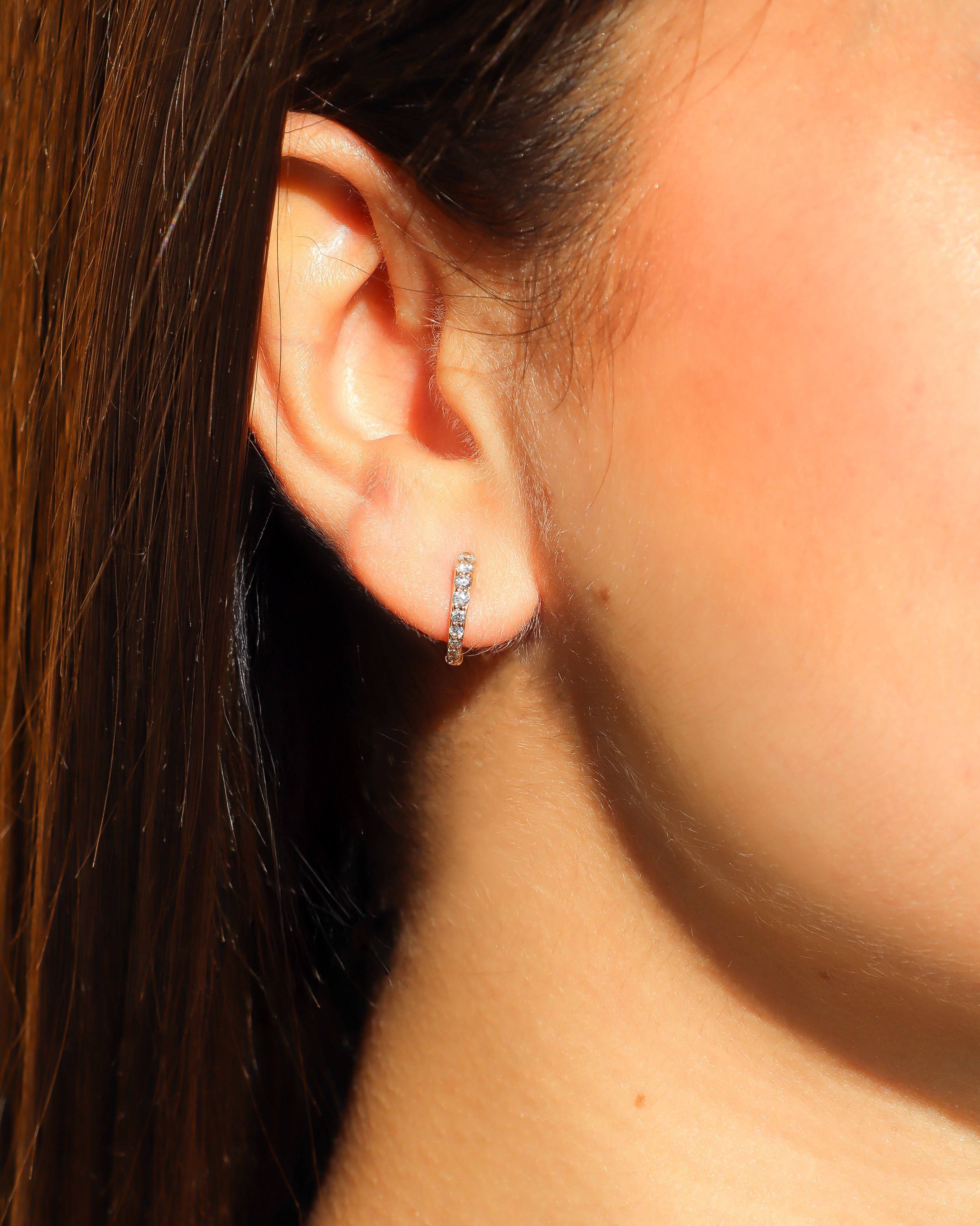 Orecchini a cerchio in oro rosa 18 carati con diamanti incastonati lungo il profilo.
