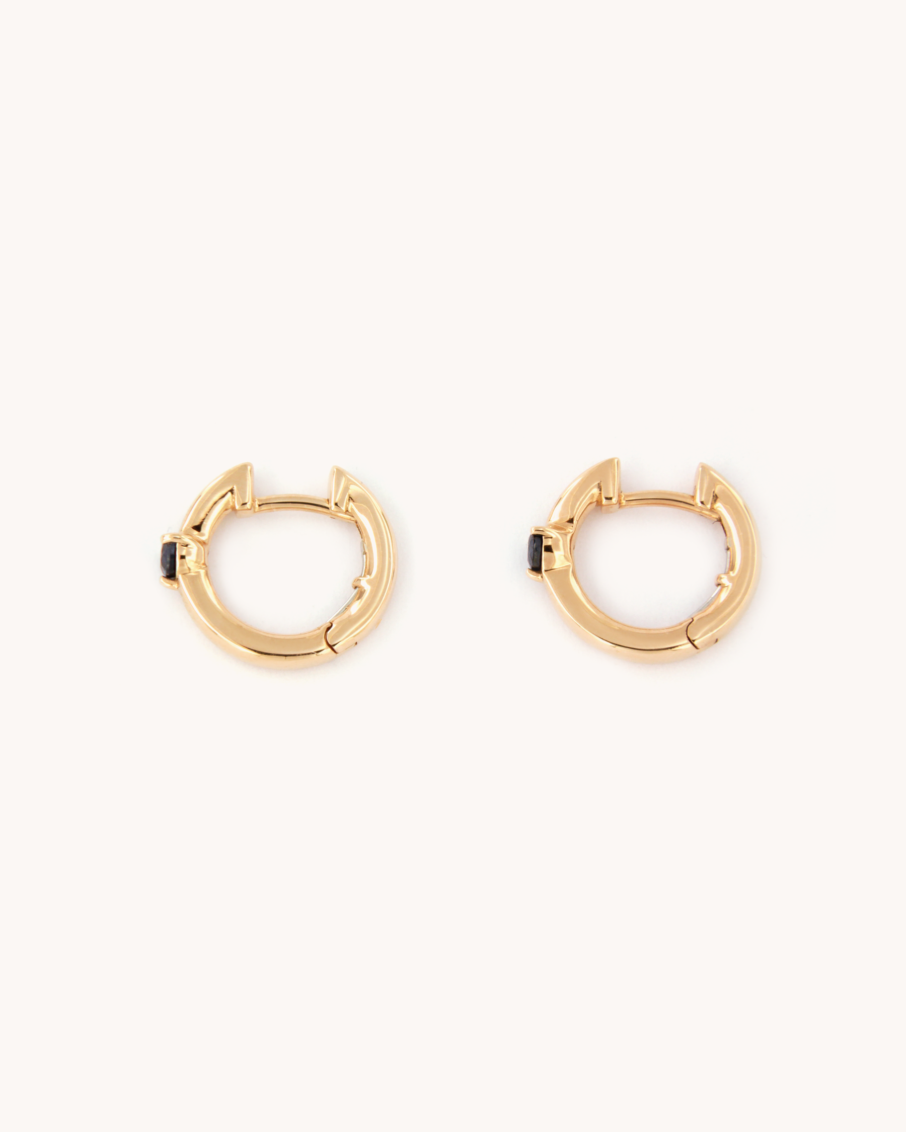 Orecchini a cerchio in oro rosa 18 carati con zaffiro centrale.