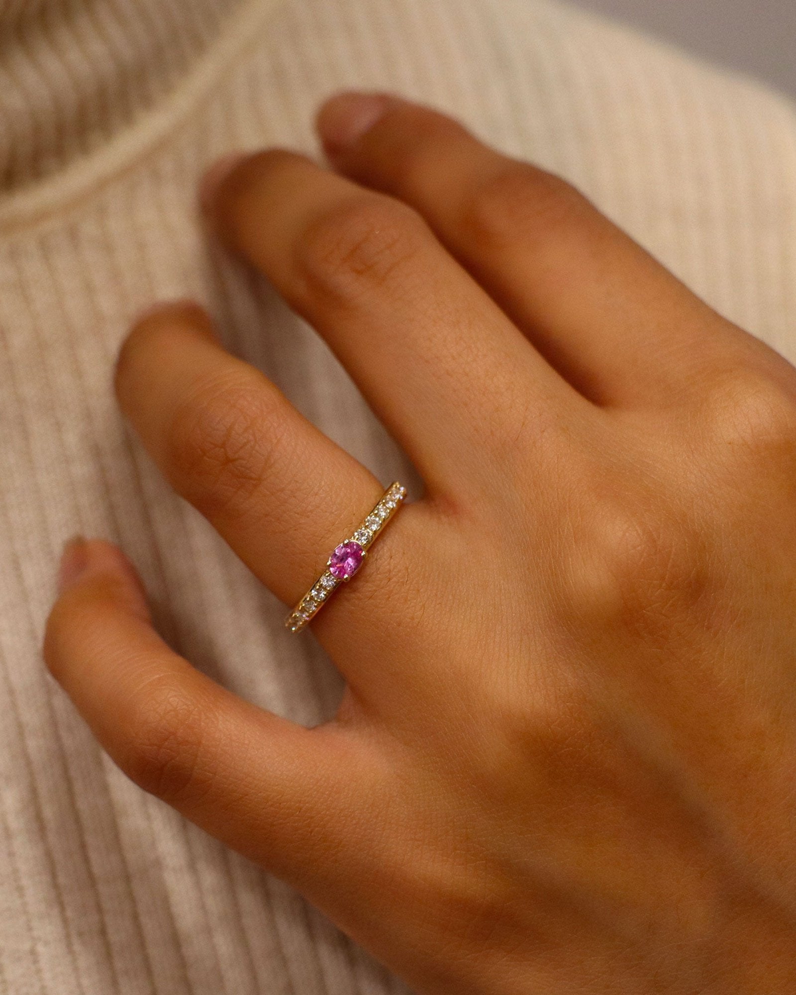 Anello oro 18K con zaffiro rosa ovale centrale e diamanti laterali.
